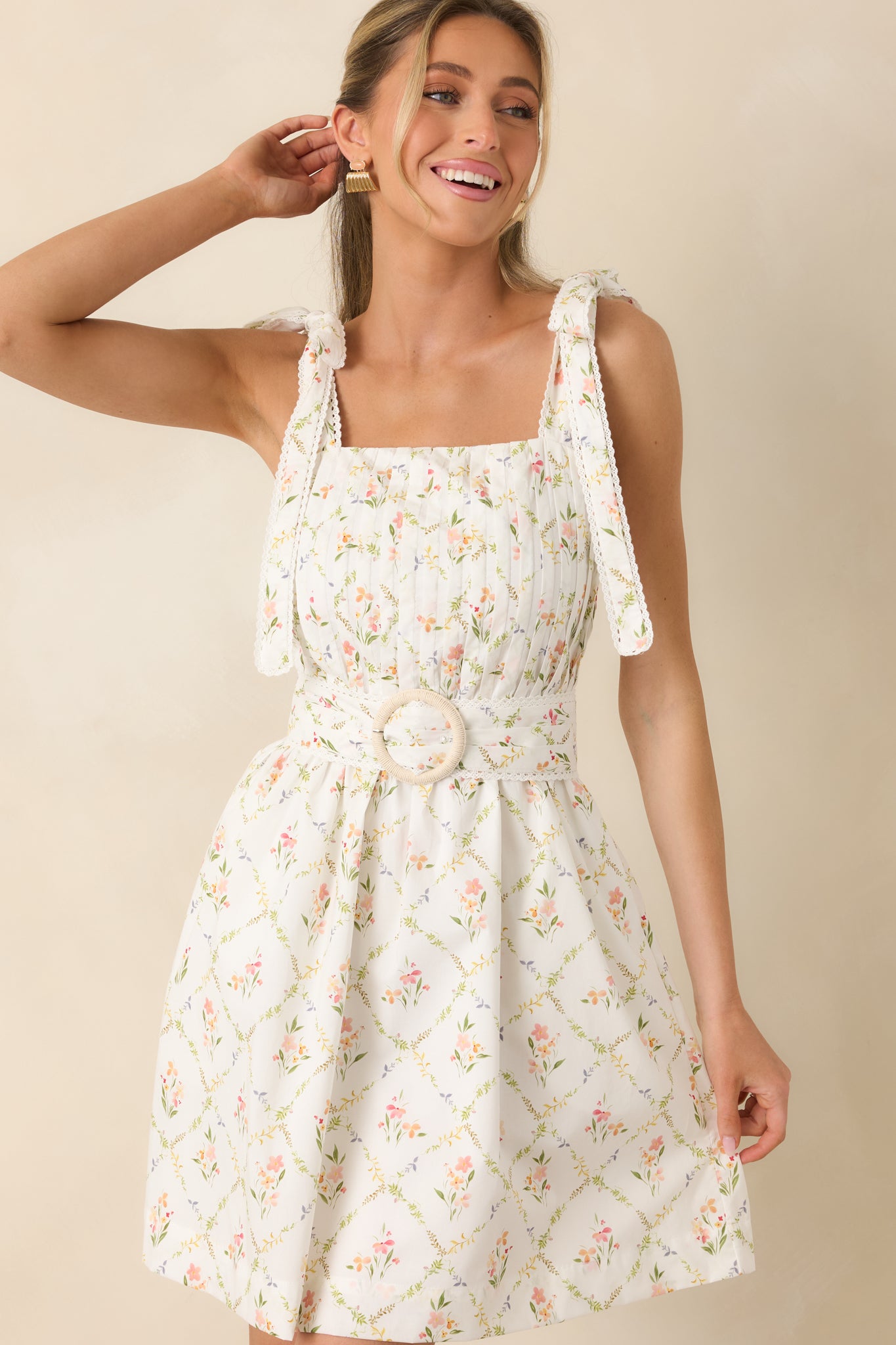 White cotton mini dress with multi floral print, pleated bodice, and tie straps.