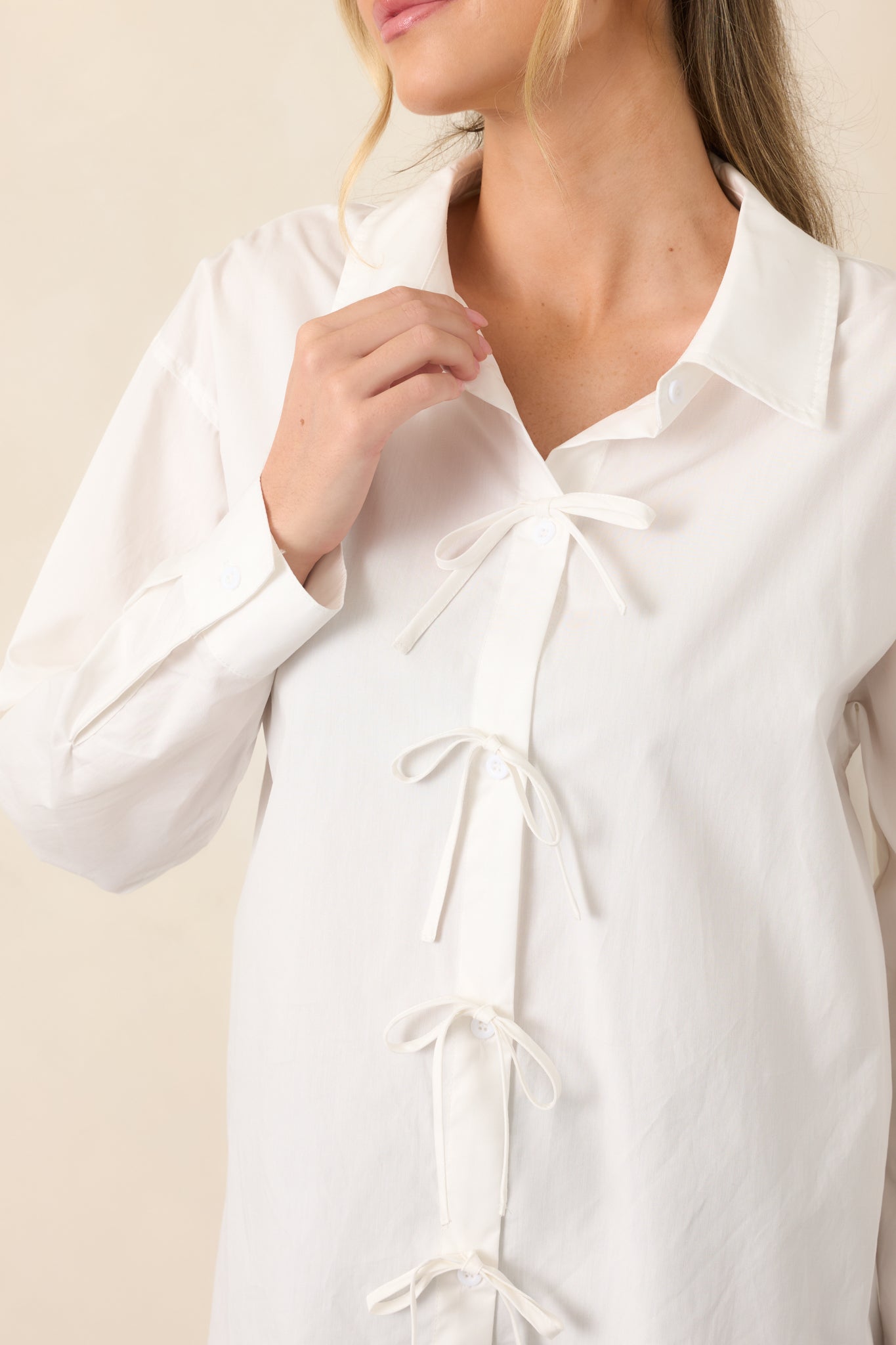 Close-up of the white cotton top highlighting the button placket and small fabric bows positioned between each button.