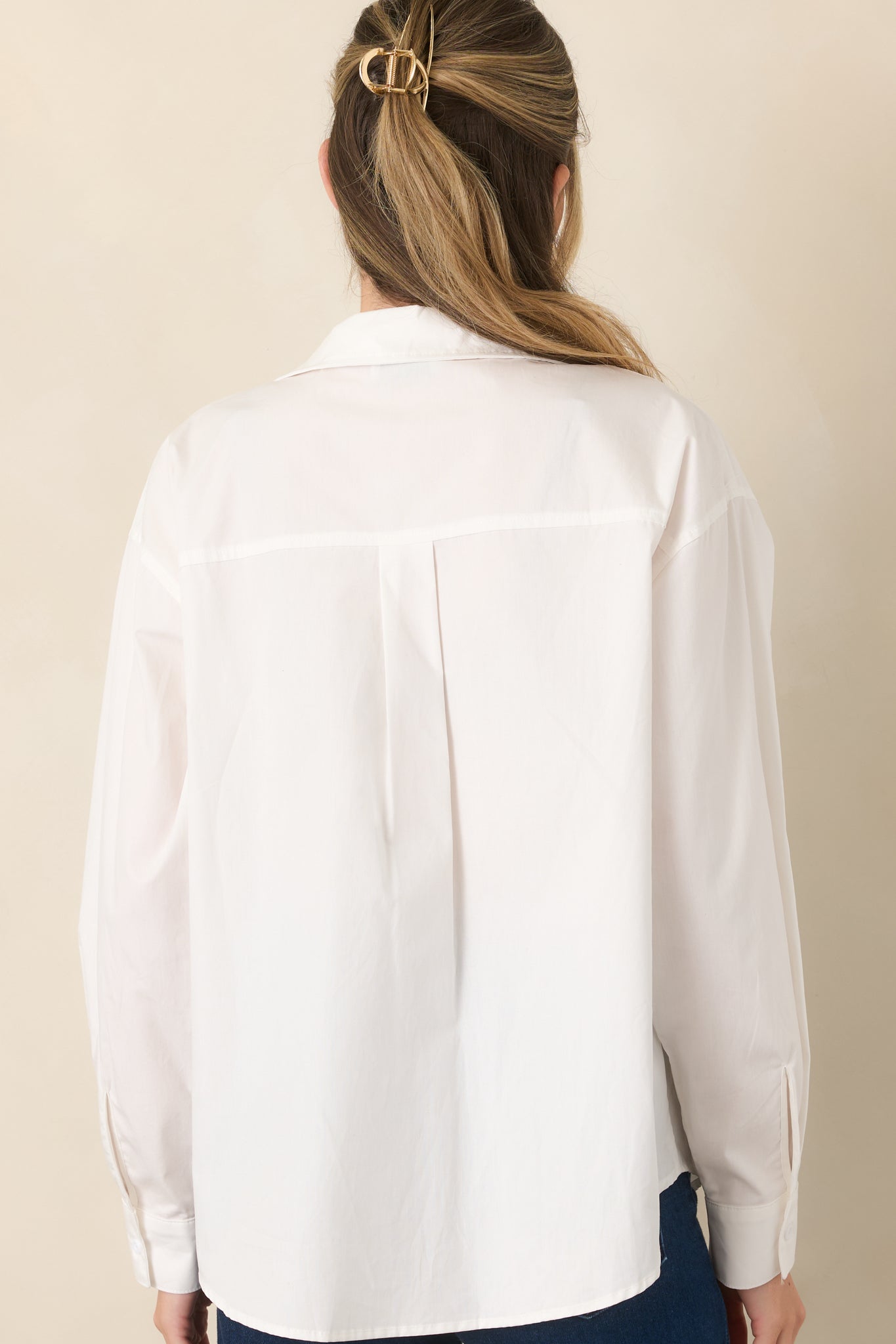 Rear view of the white cotton top showcasing its relaxed fit, collared neckline, long sleeves, and clean, unembellished finish.