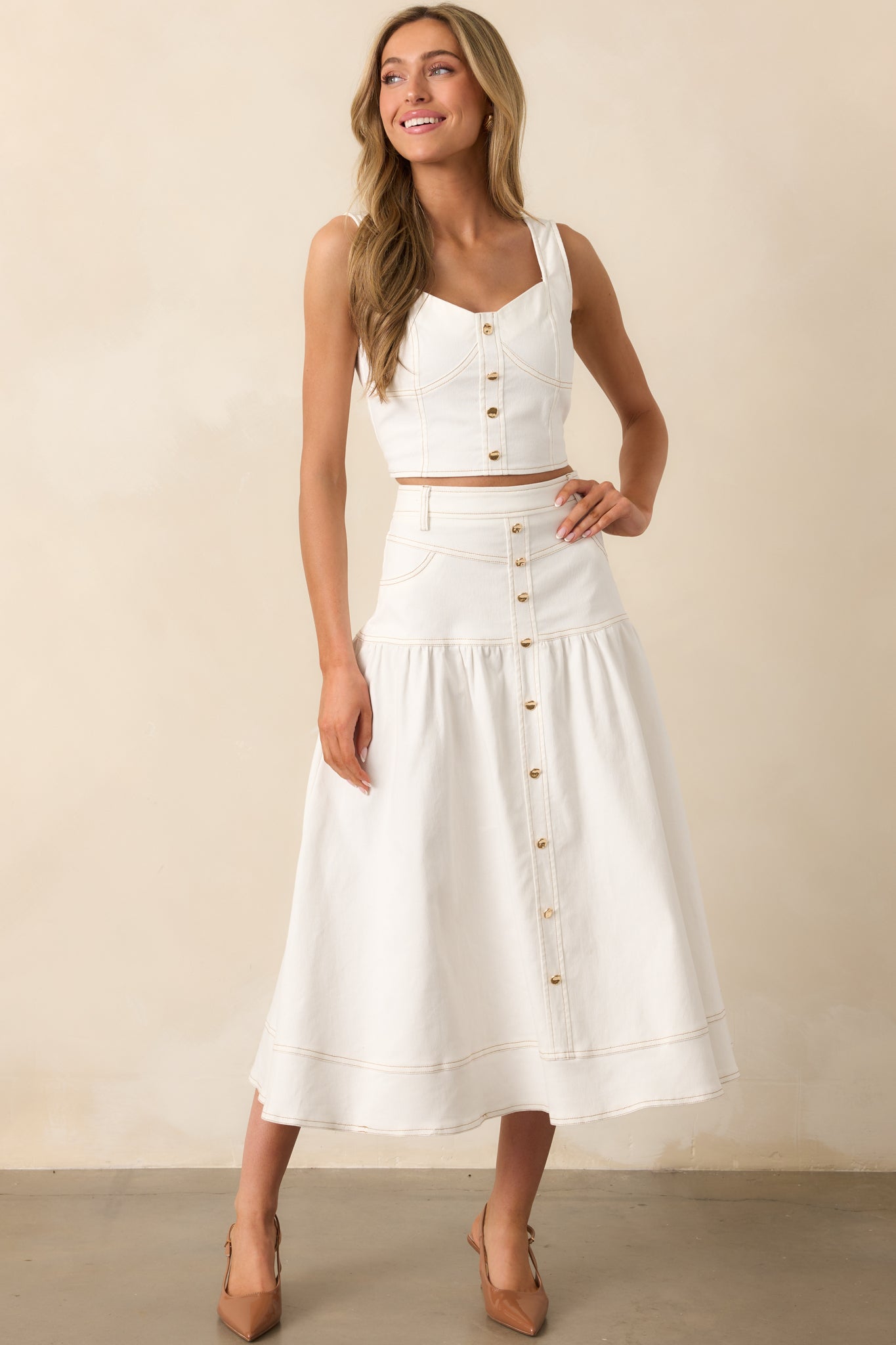 This white denim top features a faux gold button front and tan topstitching for a panelled design.