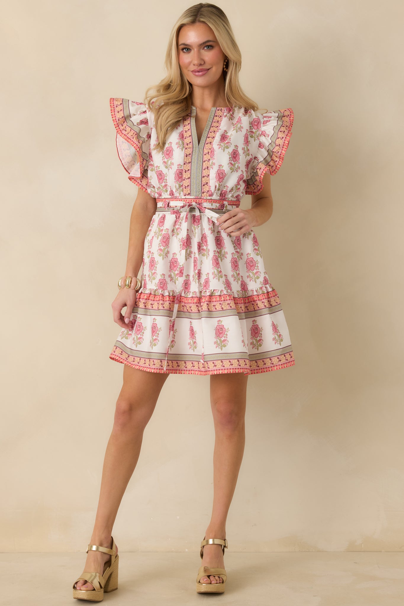 White mini dress shown from the front, highlighting the flutter sleeves, tiered hem, and colorful trim details.