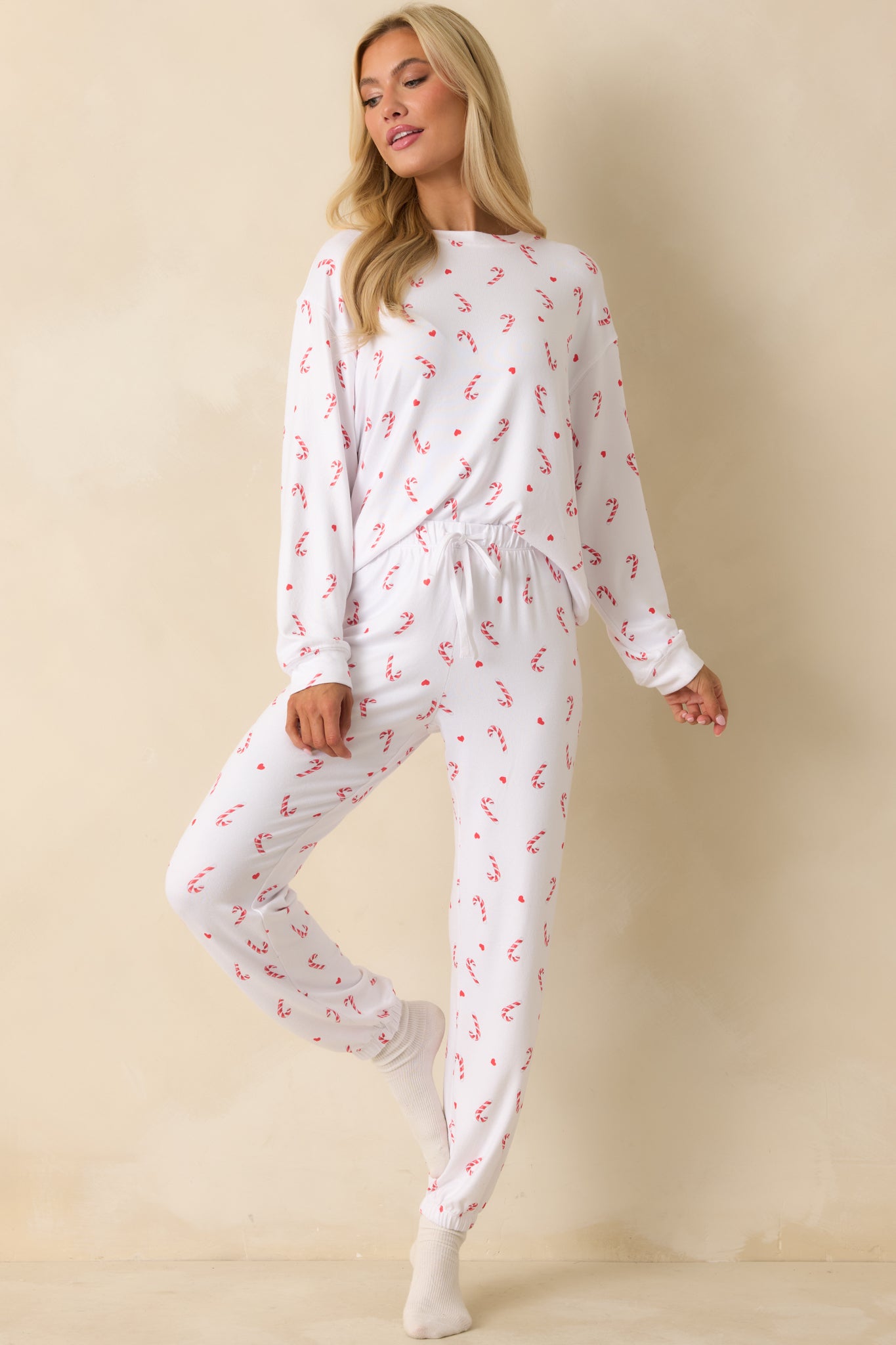 White festive knit top featuring a relaxed fit and silky jersey fabric with an allover candy-cane print.