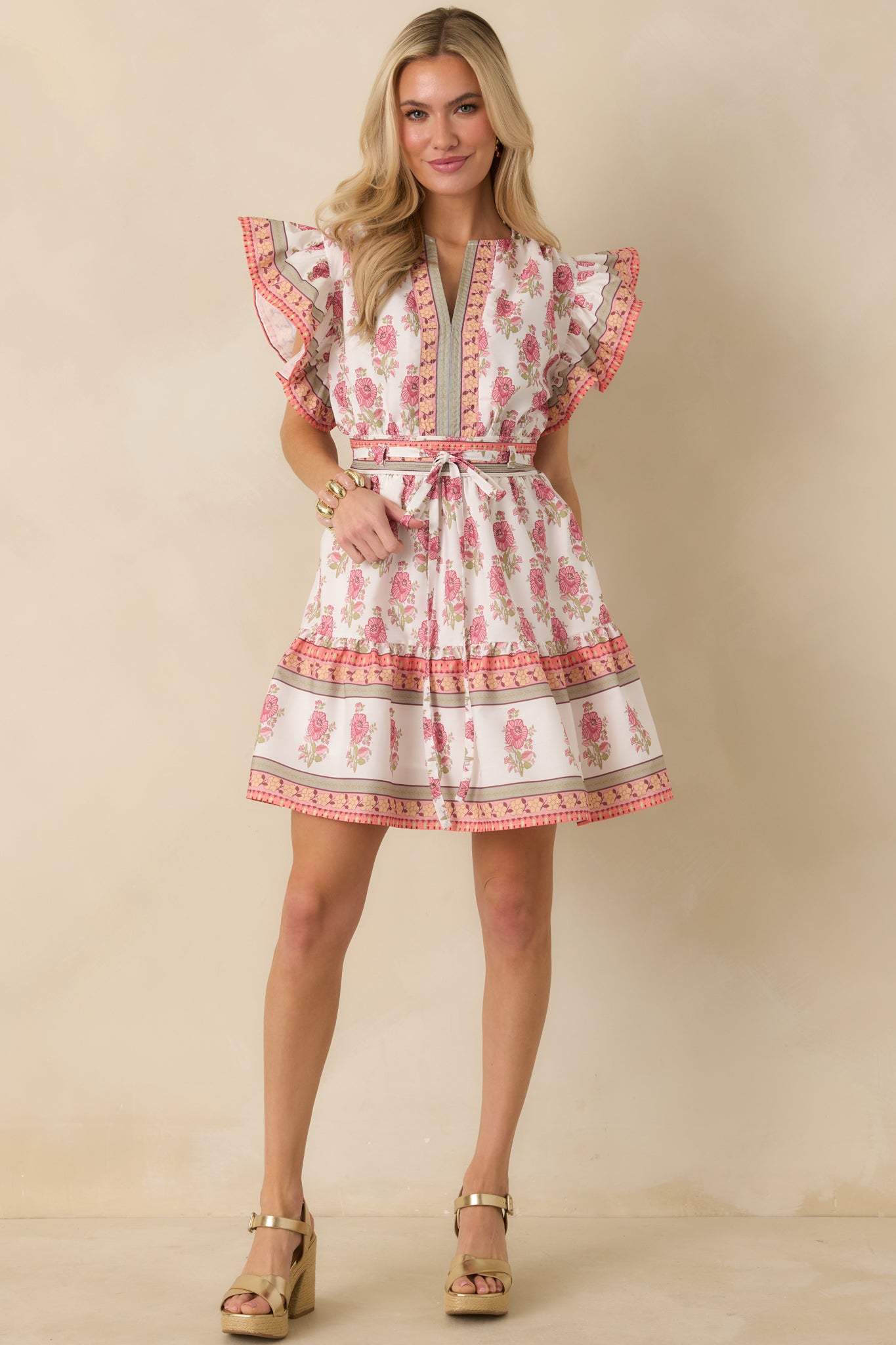Front view of a white floral mini dress featuring an elastic back waistband, optional fabric belt, and functional side pockets.