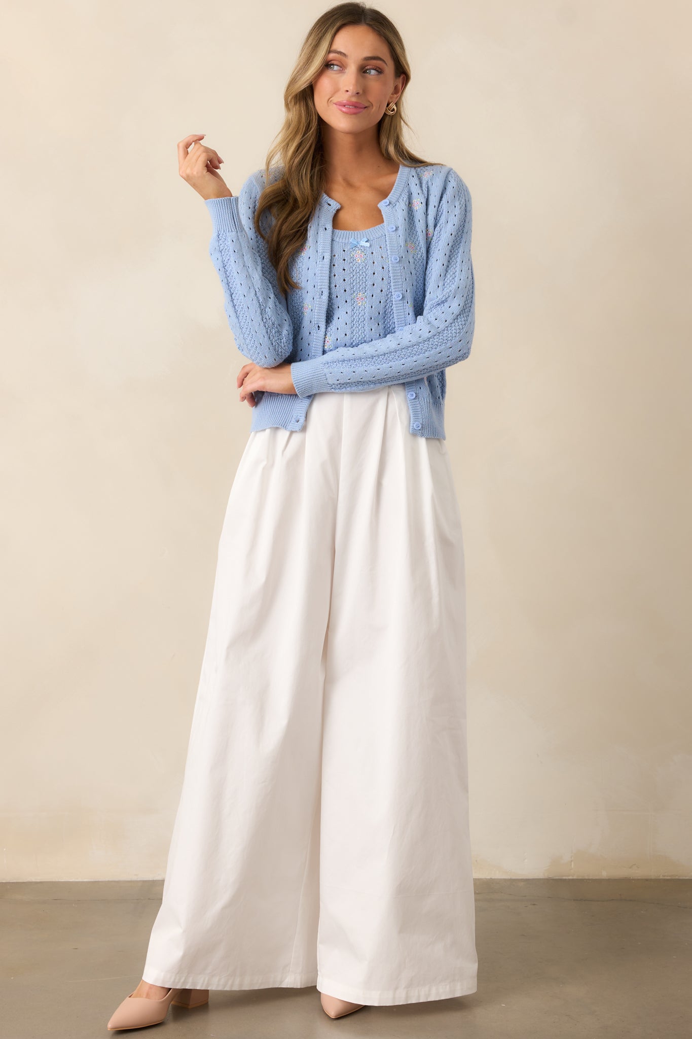 A full-length view of the white high-waisted pants with a wide-leg design, flowing from the waist to the floor, showcasing their elegant drape.