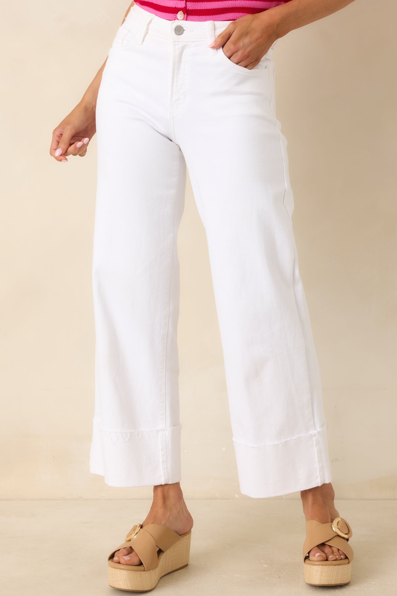 Close view of white jeans highlighting the high-rise waistband, button closure, and smooth denim texture.