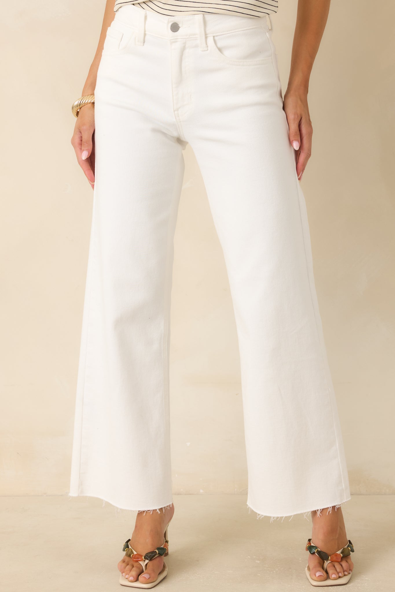 Close view of the white jeans highlighting the high-waisted waistband, button closure, and pocket details.