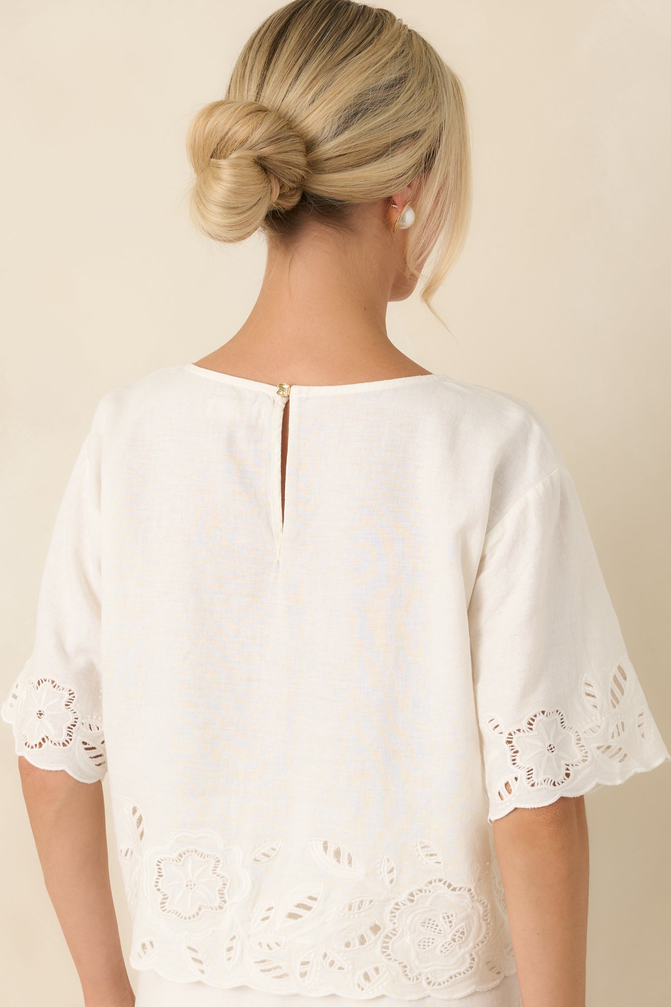 Back of the white linen-blend top featuring a delicate keyhole closure and a relaxed silhouette.