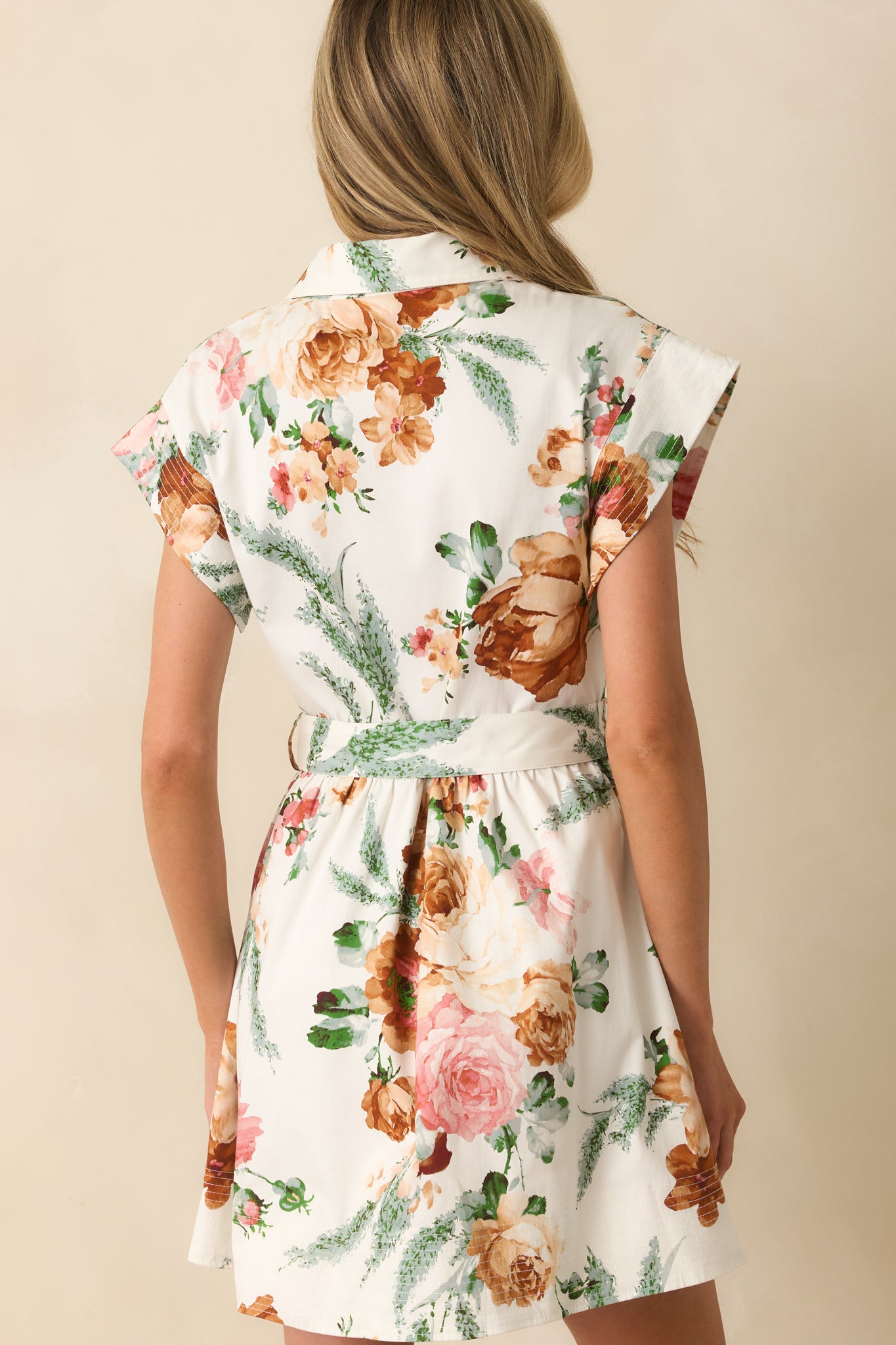 A back view of the white mini dress showing short sleeves, functional pockets, and a relaxed fit.