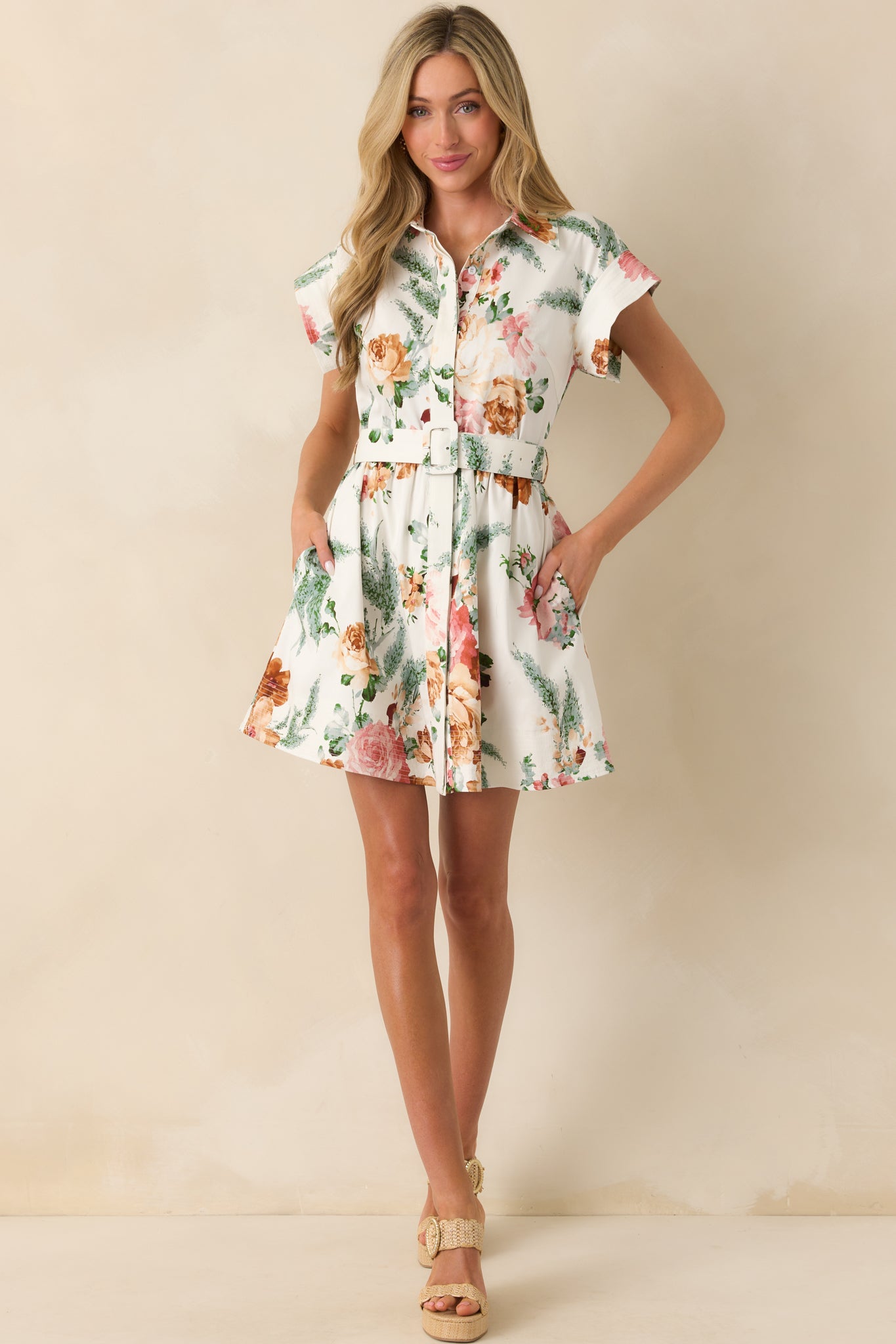 Front-facing full view of the white mini dress featuring a pink and green floral print, collared neckline, and short sleeves.