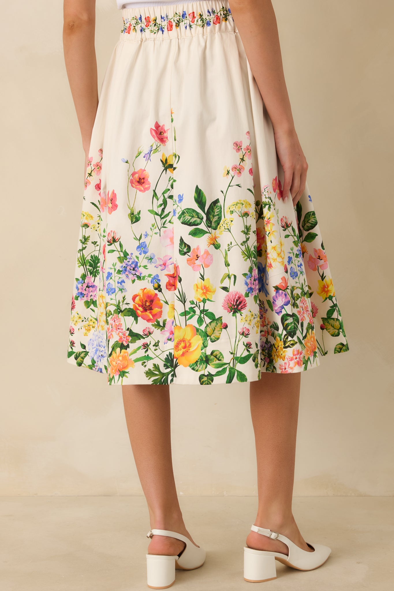 White multicolor floral midi skirt with elasticized waistband and A-line silhouette viewed from the rear.