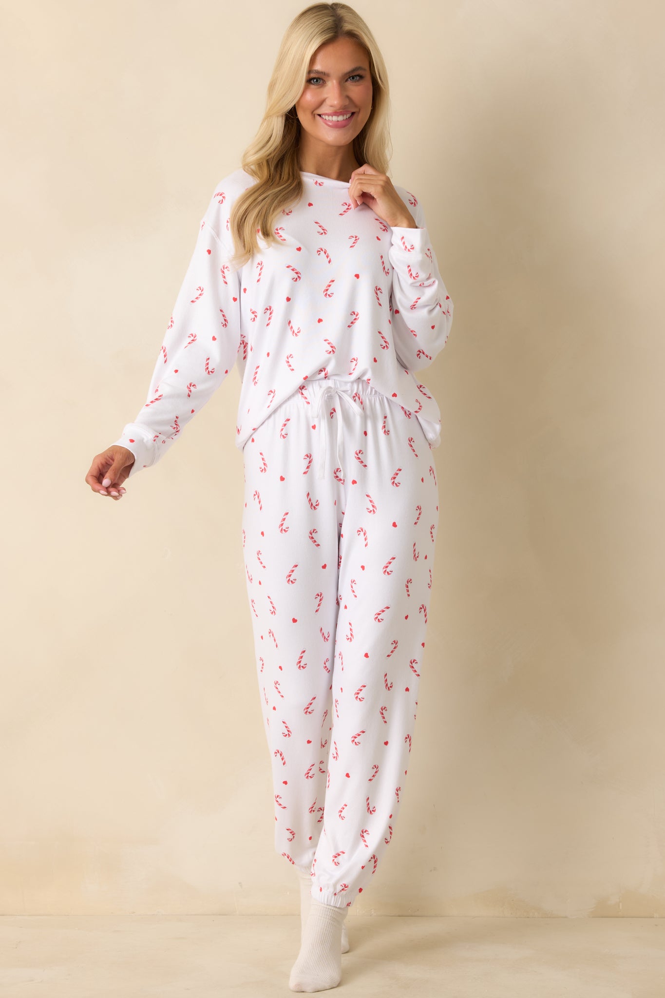 Front view of white knit pajama pants with relaxed fit, elastic waistband, full-length silhouette, and cuffed hems in silky jersey fabric.