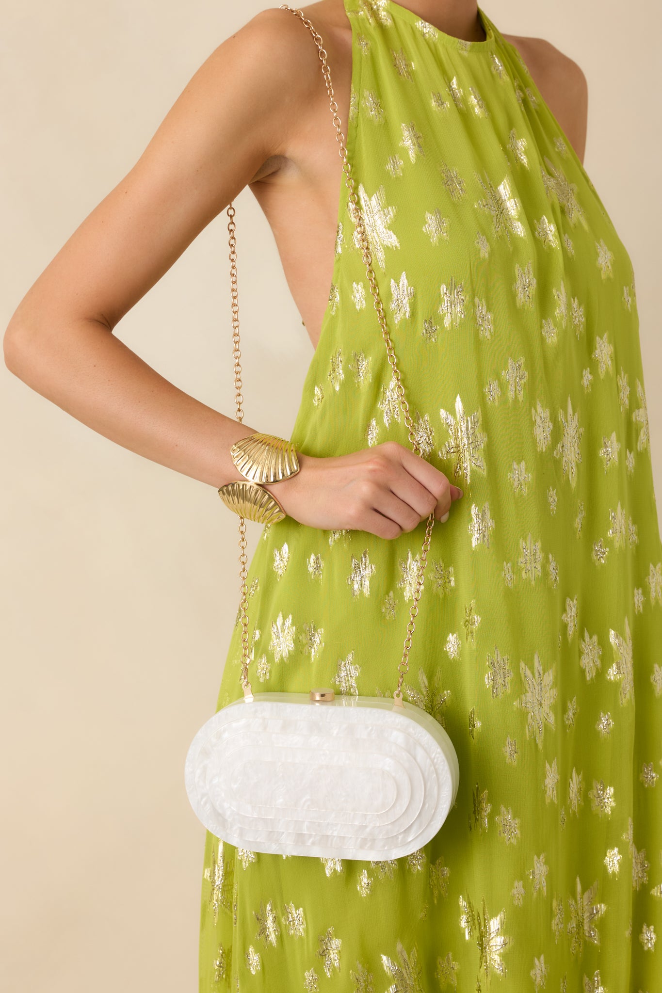 White pearlescent clutch with a structured oval silhouette, smooth luminous finish, and a polished top clasp closure.