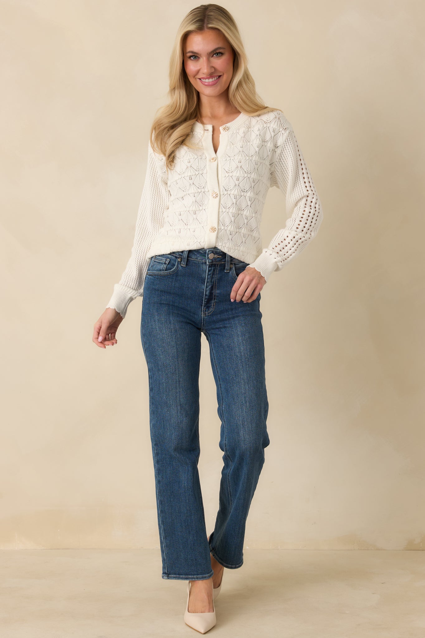 Front view of a white pointelle knit cardigan featuring long sleeves and ribbed trim at the neckline, cuffs, and hem.