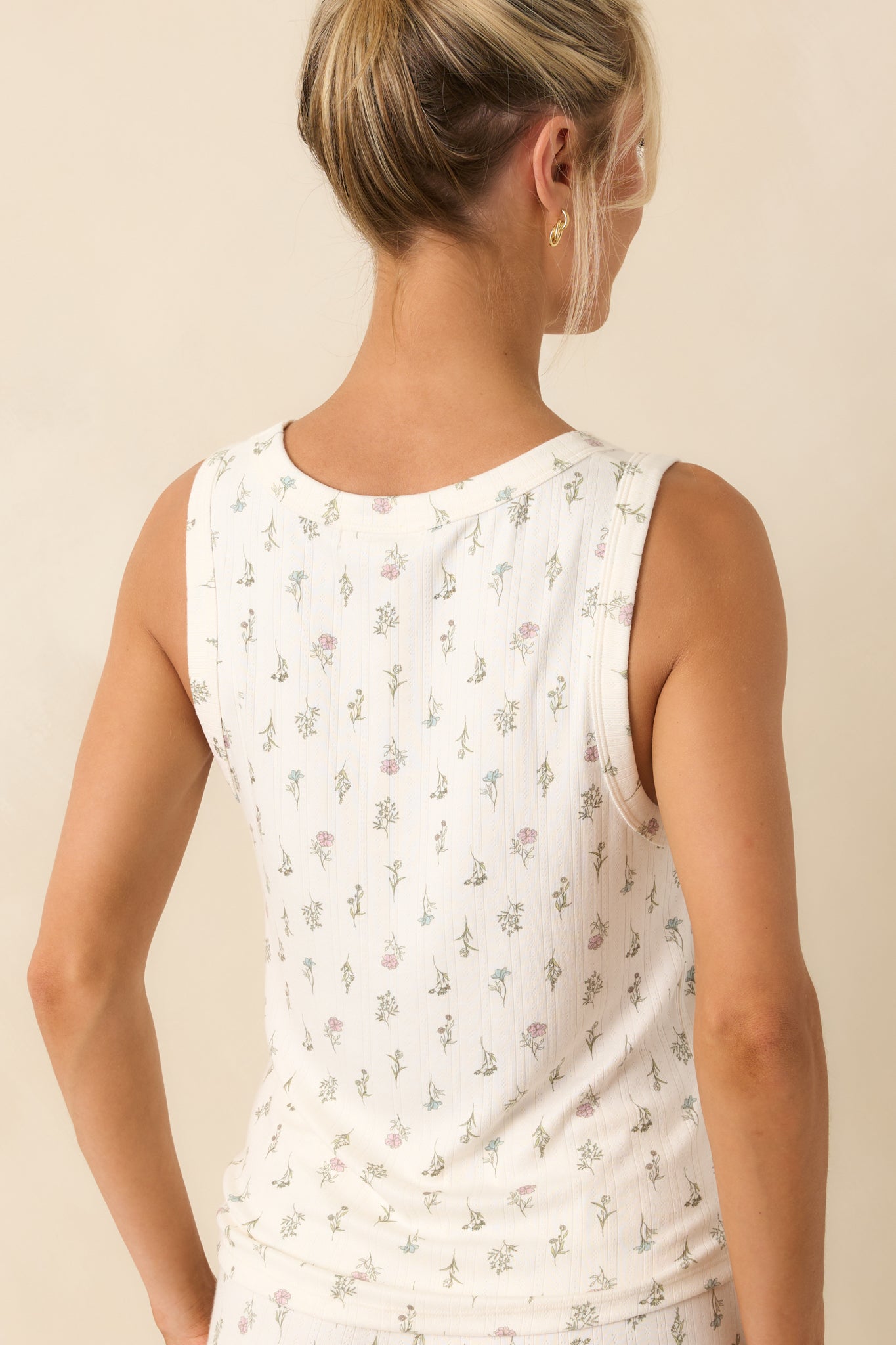 A view from behind of the white floral tank, displaying the sleeveless design, round neckline, and relaxed shape.