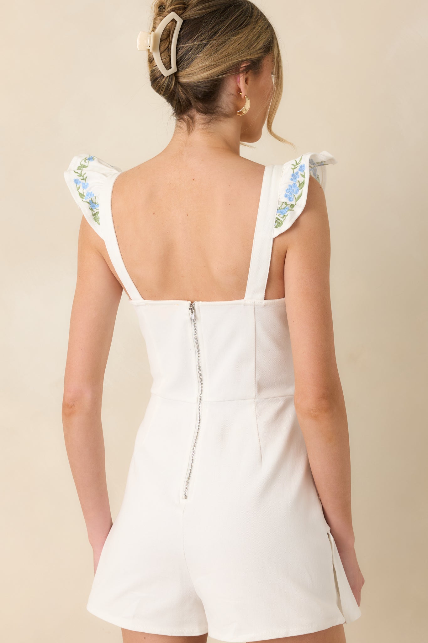 White romper with clean back zipper closure and structured fit through the bodice.