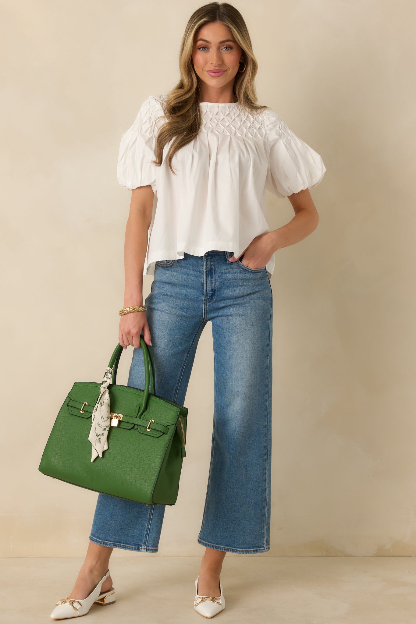 White short-sleeve top shown from the front, highlighting the textured smocked yoke and round neckline.