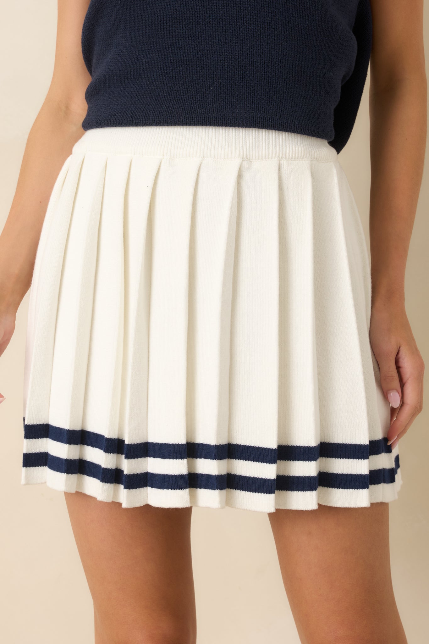 Close view of the white skirt highlighting the elastic waistband, pleats, and soft knit texture.