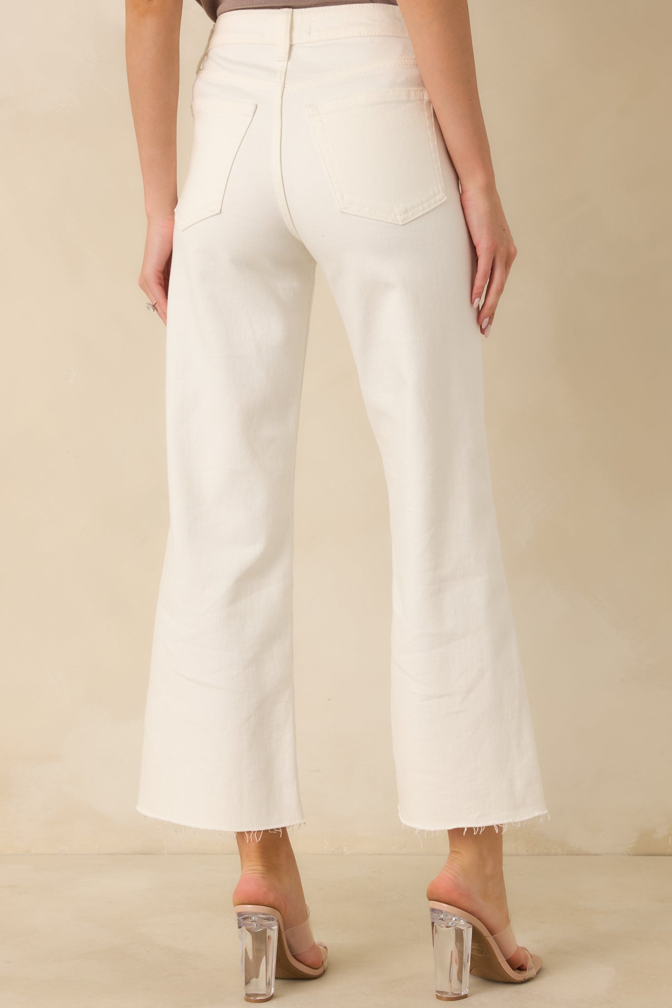 White wide-leg jeans with back pockets, raw hem, and slightly cropped length.