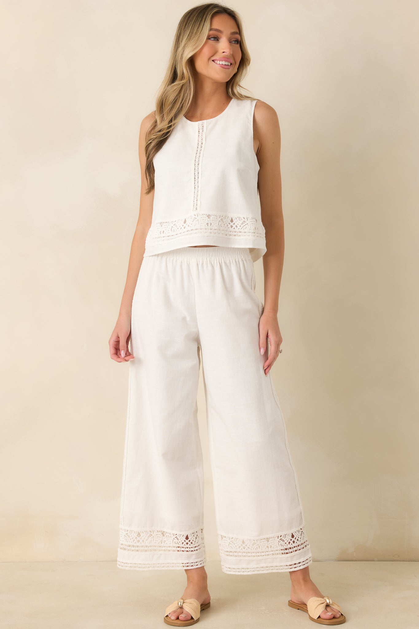 White wide-leg pants crafted from a breathable cotton-linen blend featuring an elastic waistband, ankle-length hems, and delicate lace trim detailing along the sides.