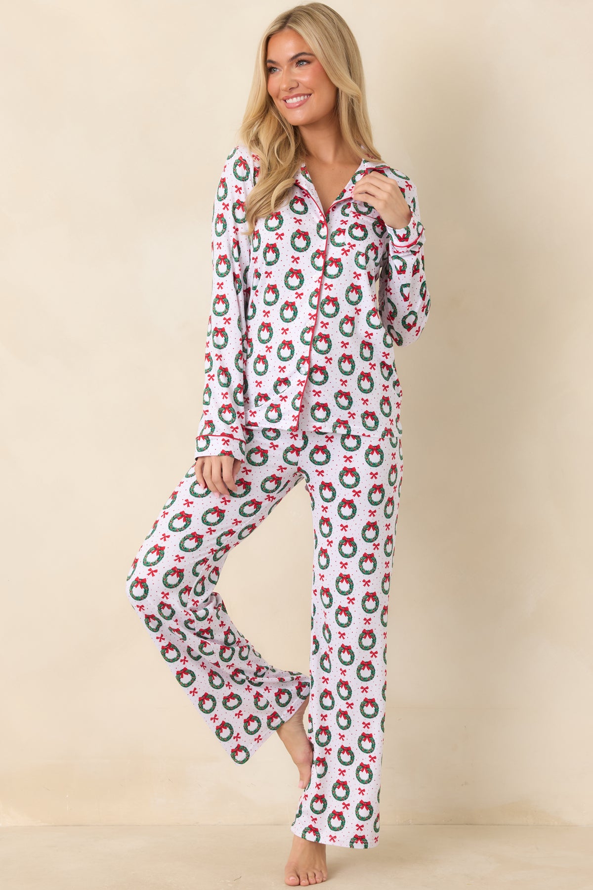 White pajama pants feature an allover wreath and bow print with black piping and a relaxed straight-leg silhouette.