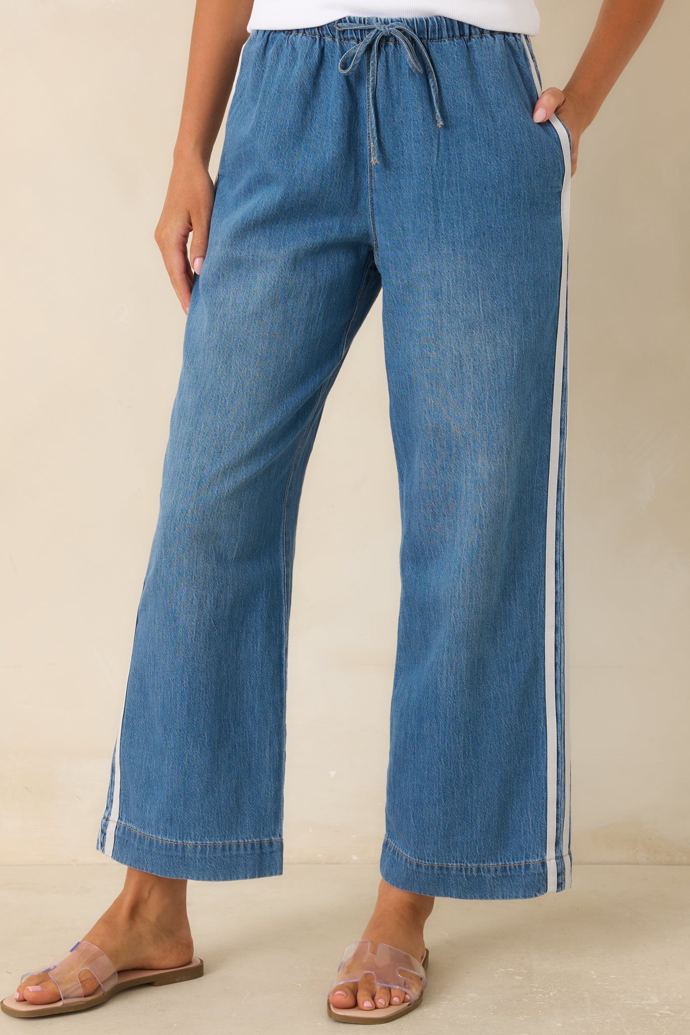 Close-up of the wide leg denim pants showcasing the sporty side stripe detail and relaxed fit through the leg.