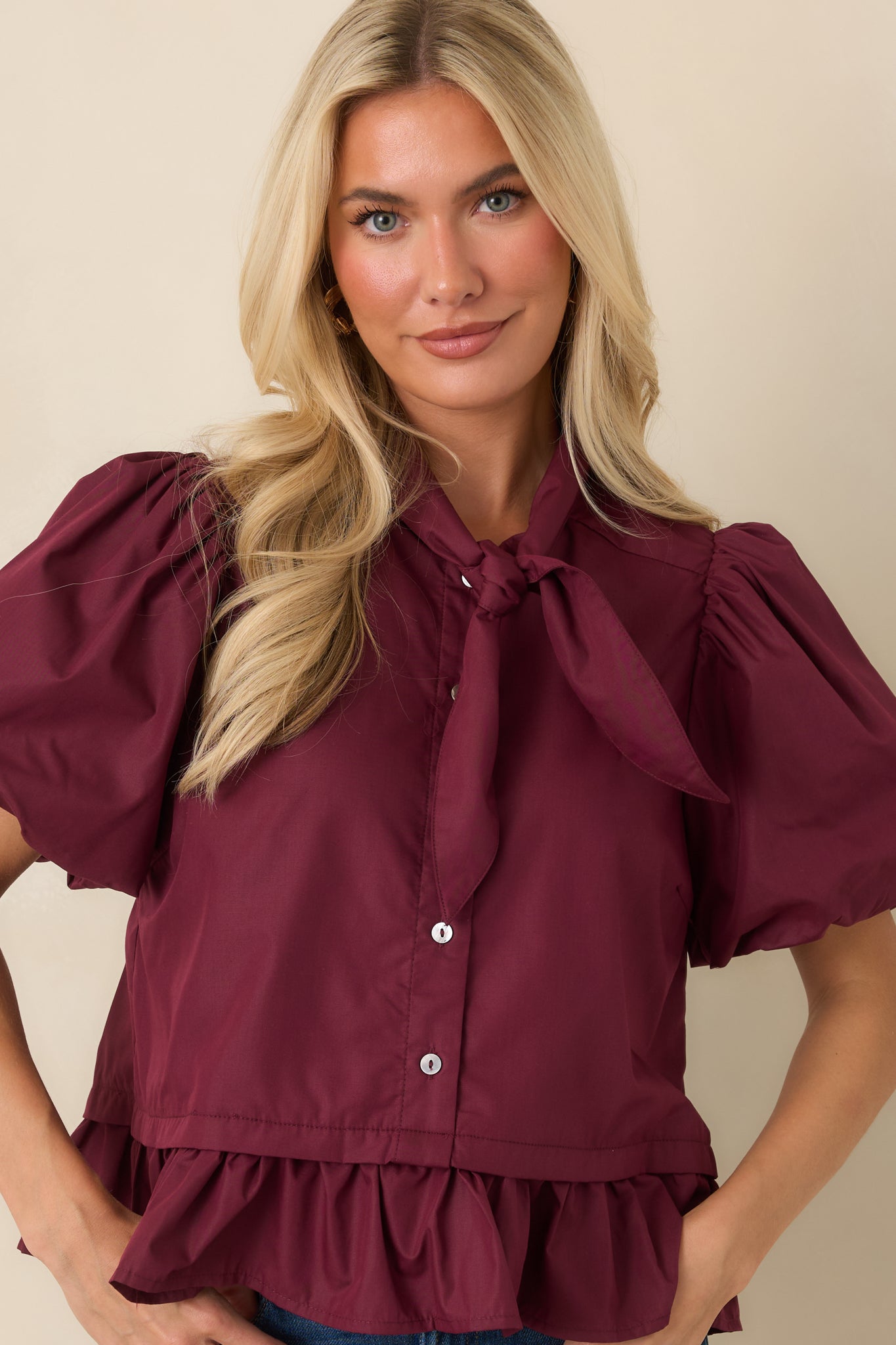 Wine blouse featuring dramatic puff sleeves and a flounced peplum hem with a polished finish.