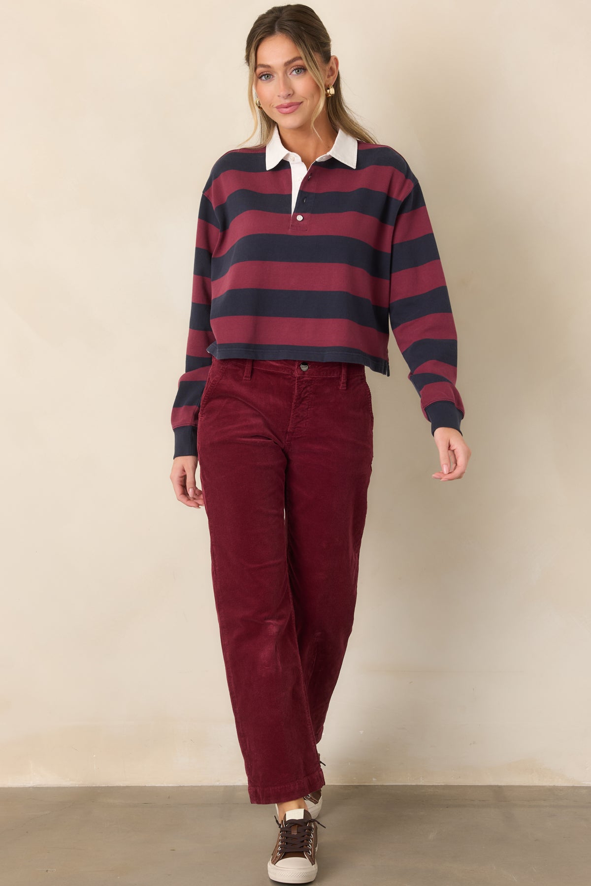 Wine-colored corduroy pants featuring a cropped straight-leg silhouette, traditional belt loops, zip fly with button closure, and slanted front pockets.