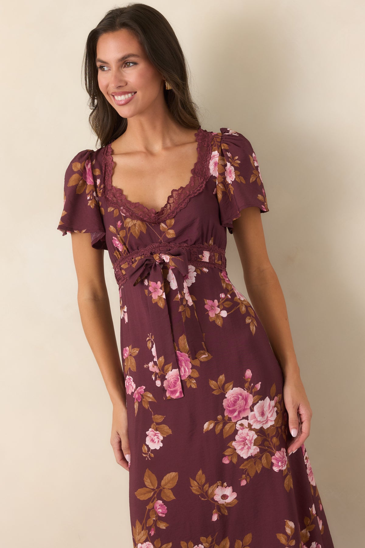 Detailed view of the raised waist featuring scalloped lace trim, a tied fabric bow, and soft gathering beneath the bust.