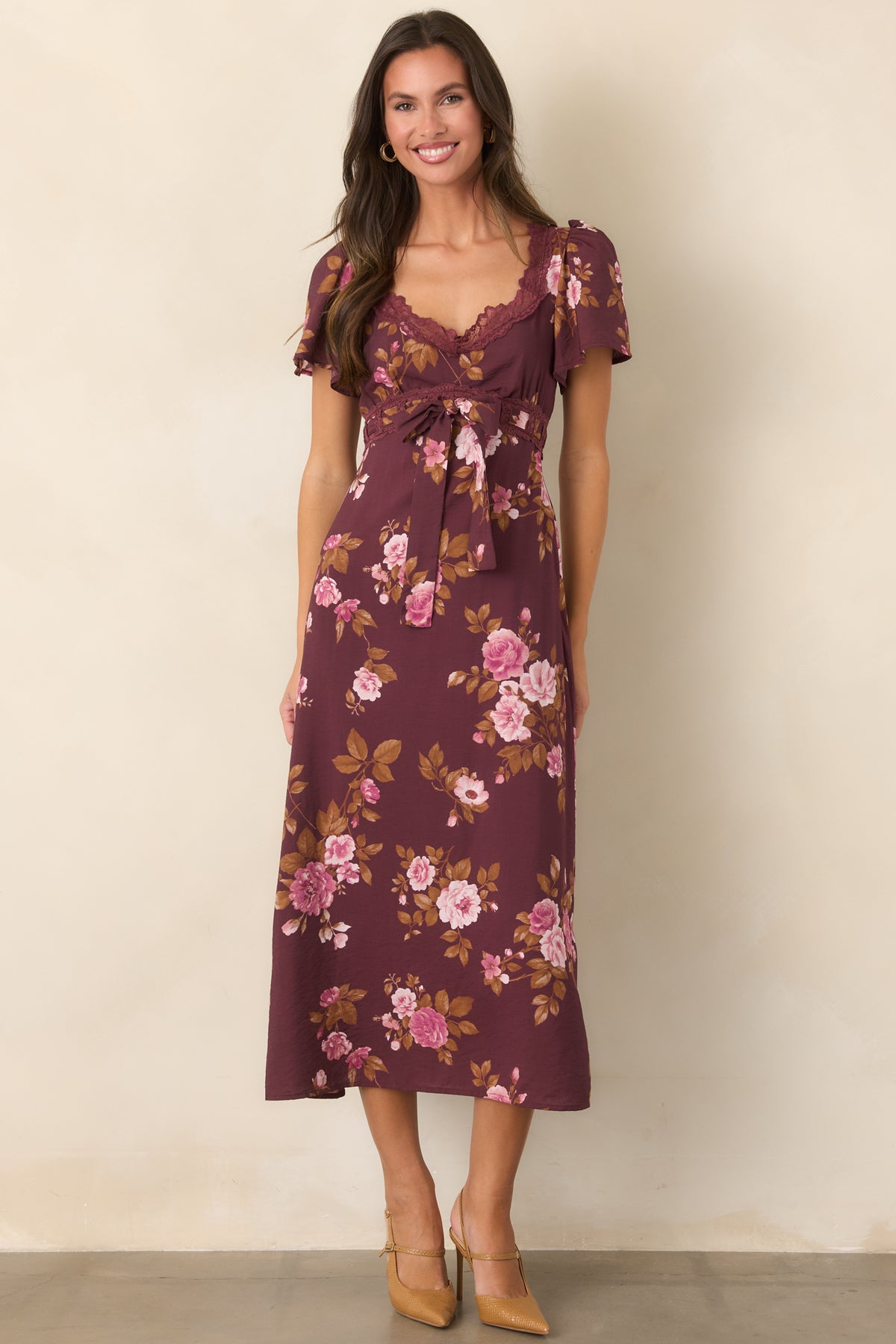 Wine-colored floral dress showcasing blush blossoms, golden brown foliage, and an adjustable waist tie above a flowing midi skirt.