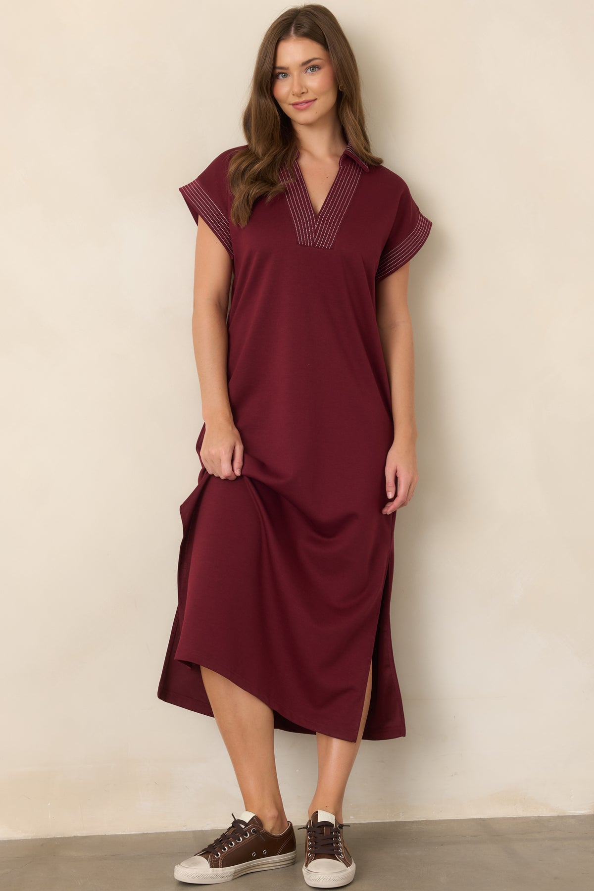 Wine hued knit maxi dress showcasing its collared V-neckline, side pockets, and softly relaxed shape.