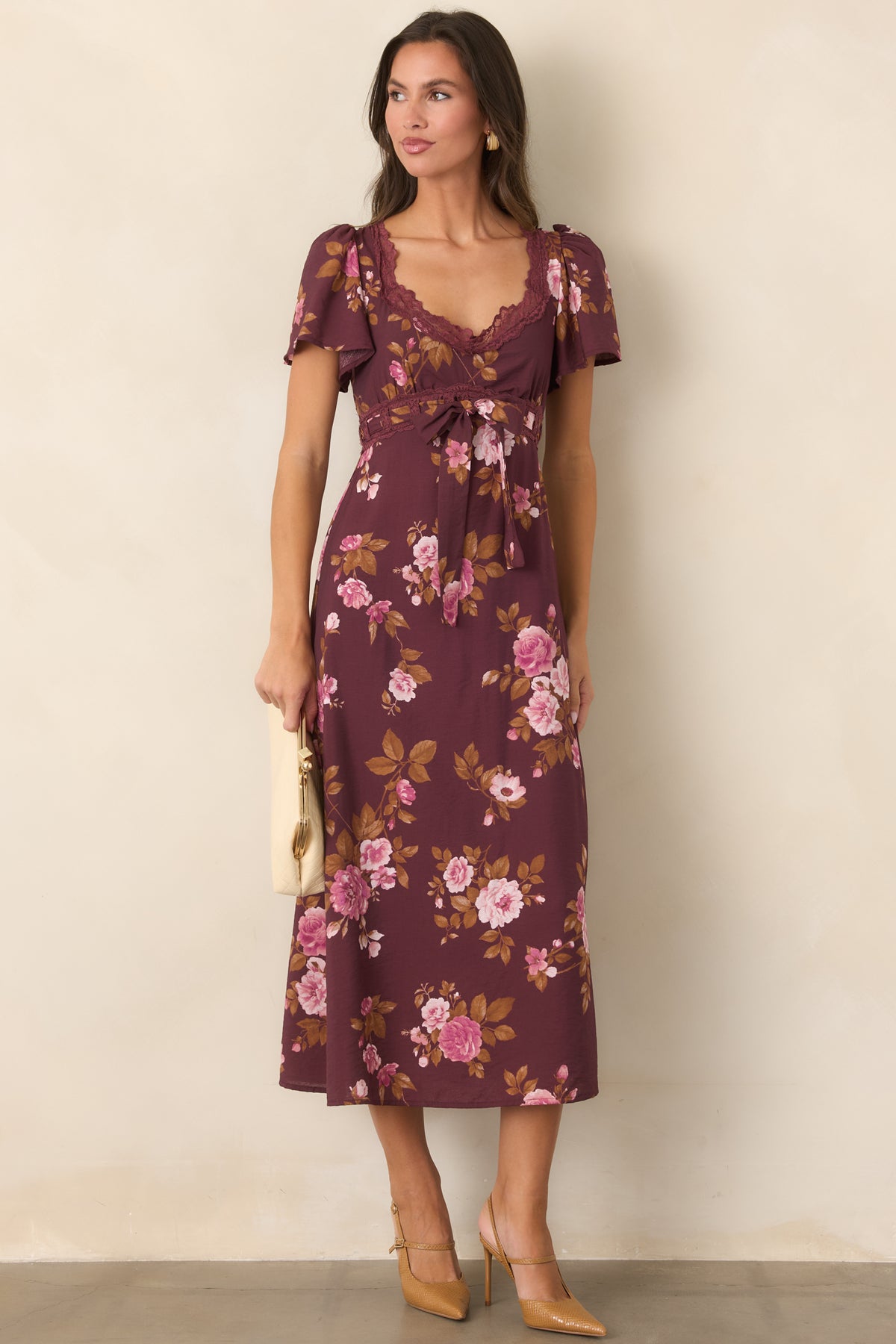 Vintage-inspired wine dress with a pink floral print, raised waist accented by a fabric tie bow, and a softly flared midi skirt.