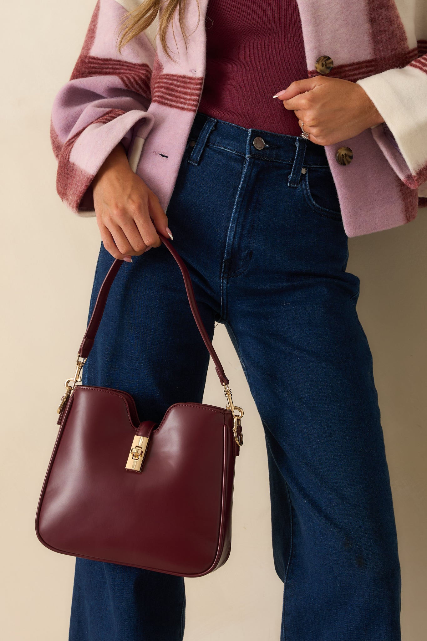 Wine red faux leather handbag with a structured silhouette and gold twist-lock closure shown from the front.