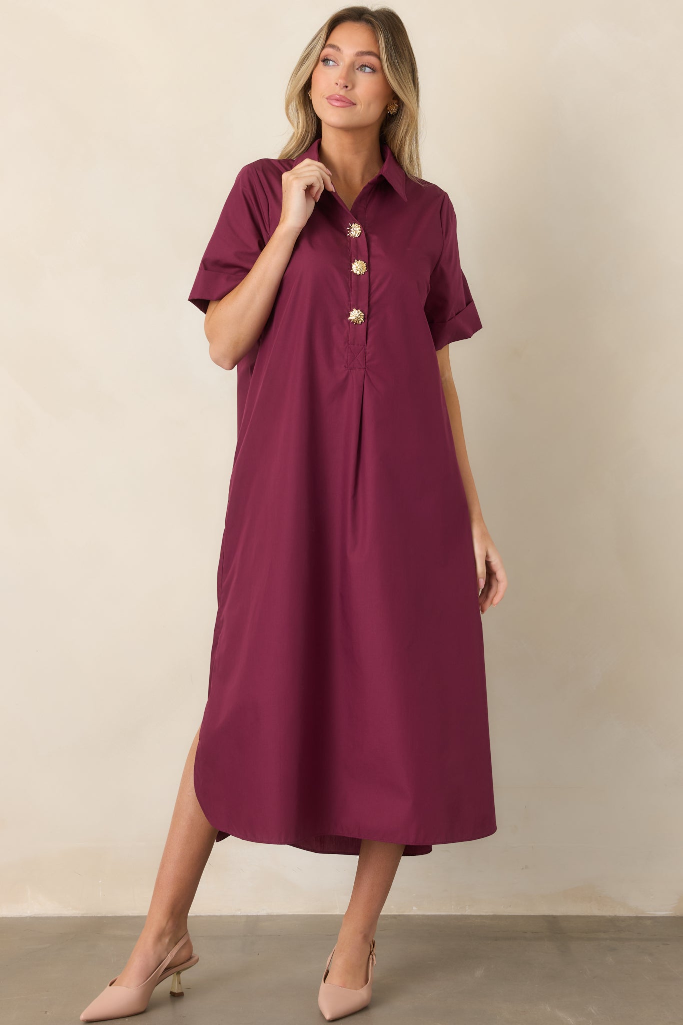 Wine red shirt-style maxi dress showcasing its relaxed A-line silhouette, collared neckline, rolled short sleeves, and decorative gold floral buttons along the front.