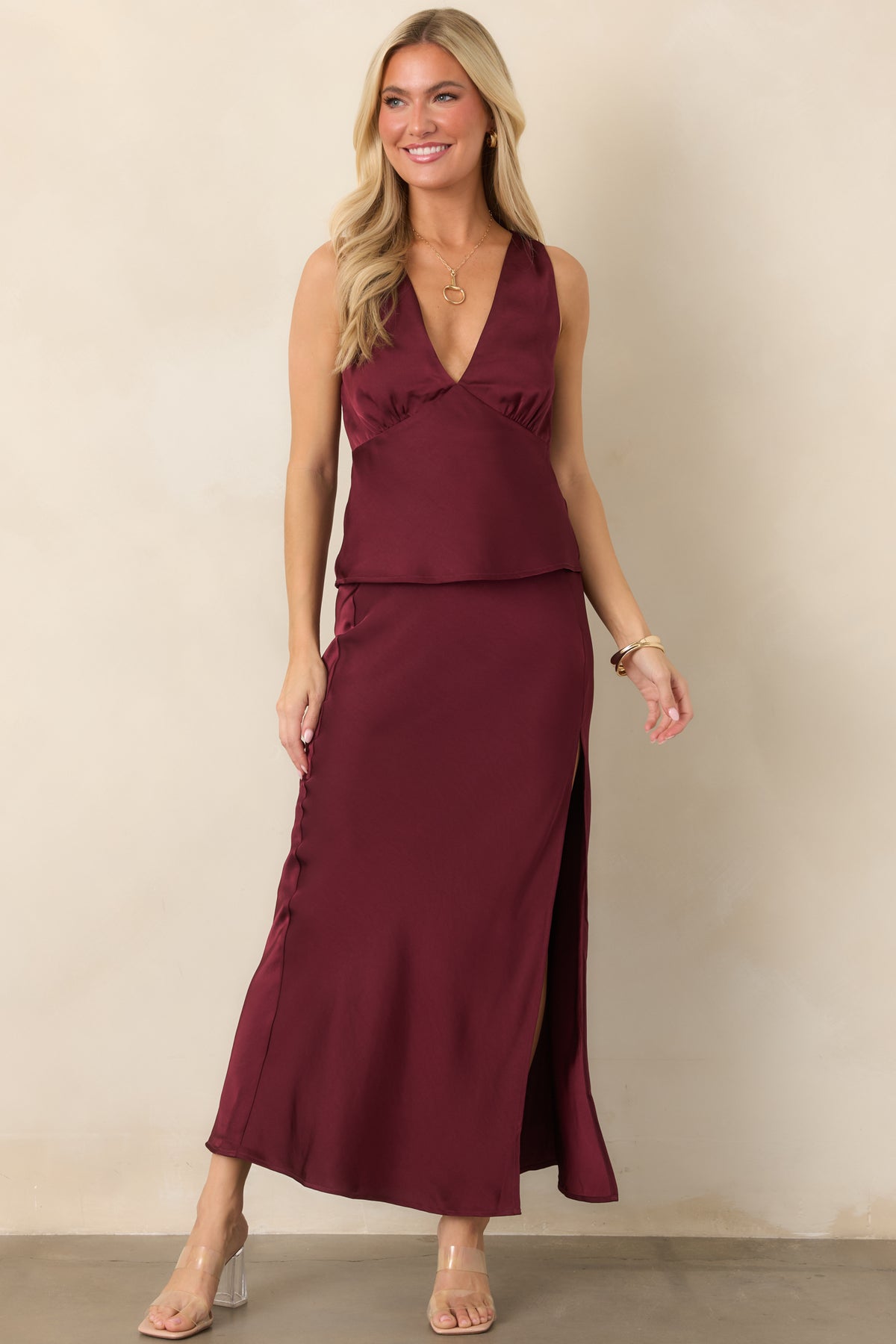 Wine satin top with a bias-cut silhouette, wide shoulder straps, deep V-neckline, and softly flared peplum hem.