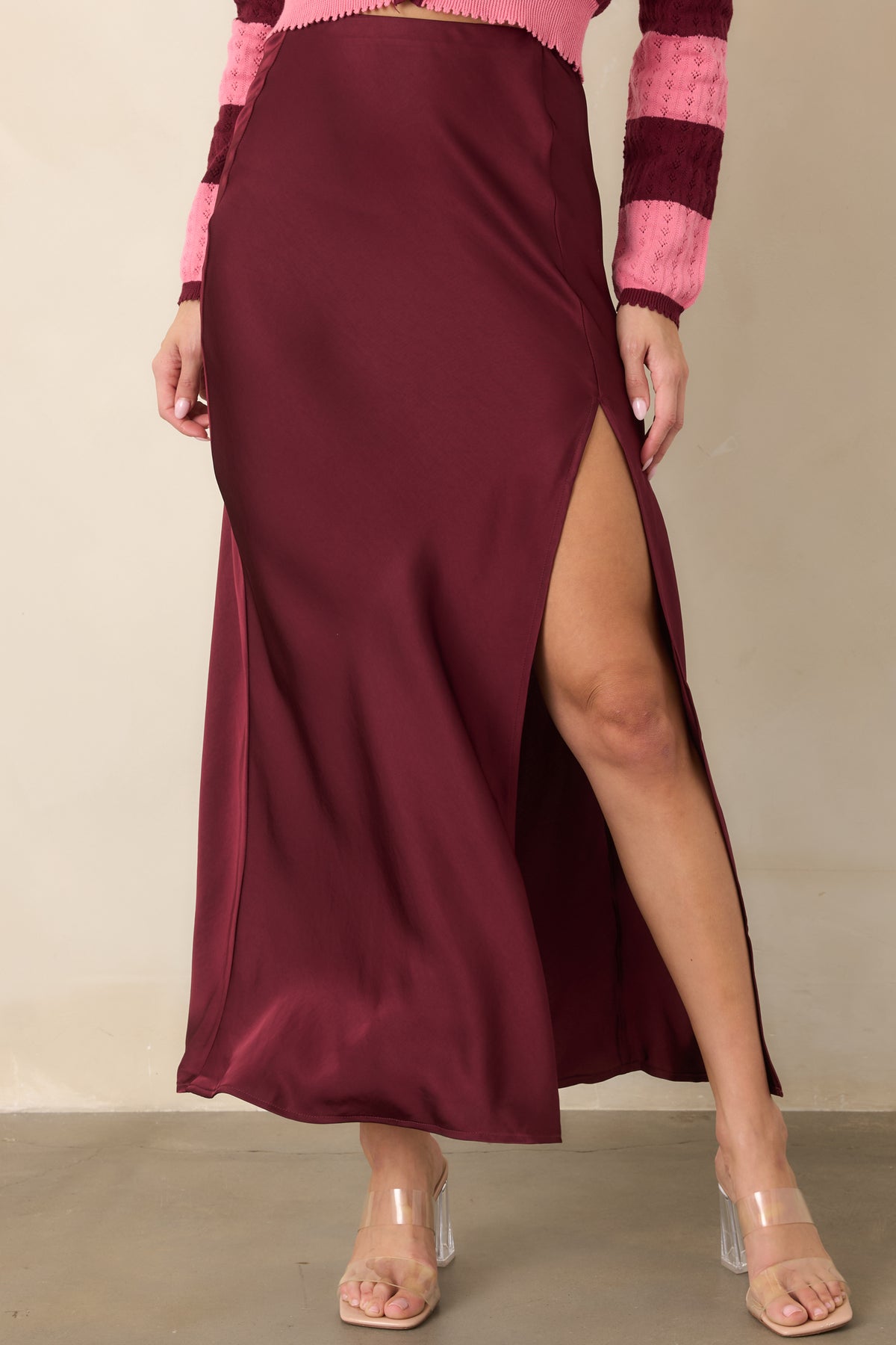 Bias-cut wine satin skirt with softly flared fabric falling from the hips to the midi hem.