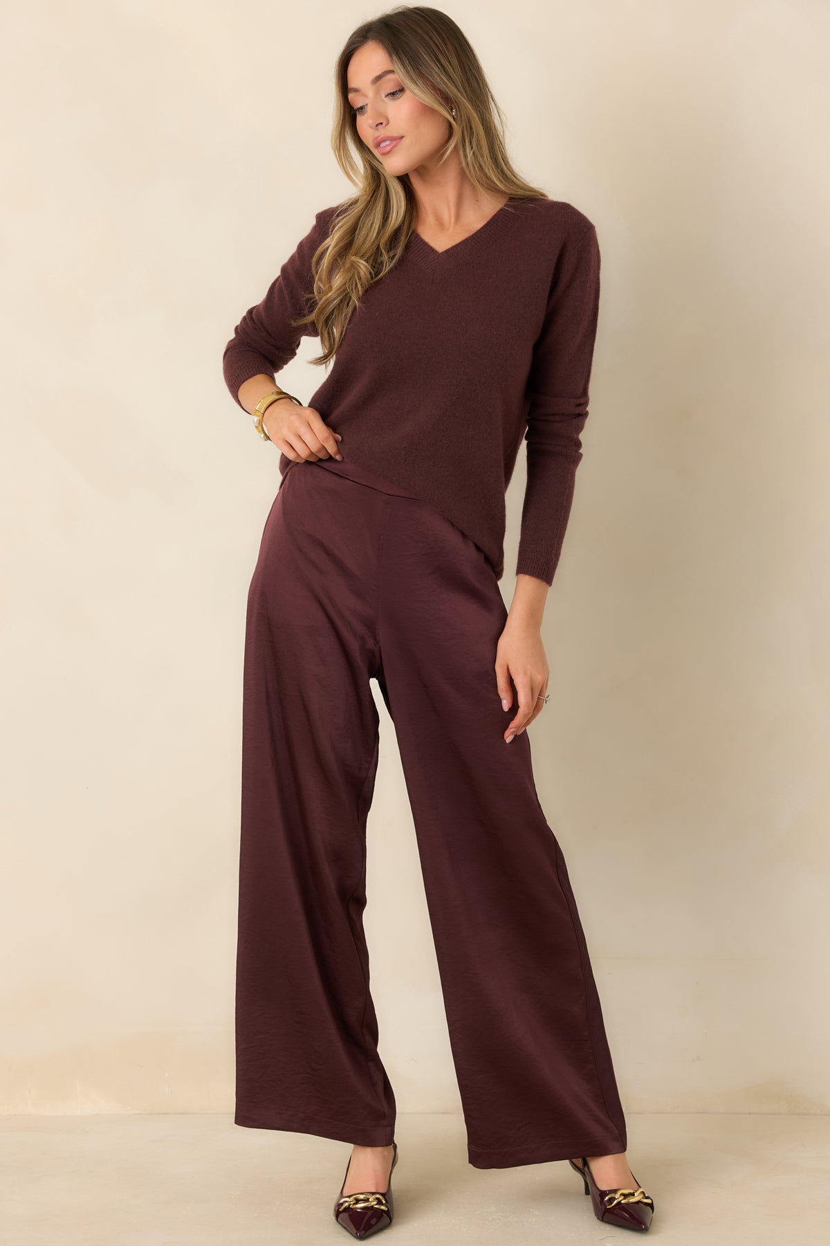 Wine-colored wide-leg pants featuring a smooth front waistband, subtle satin sheen, and relaxed silhouette.