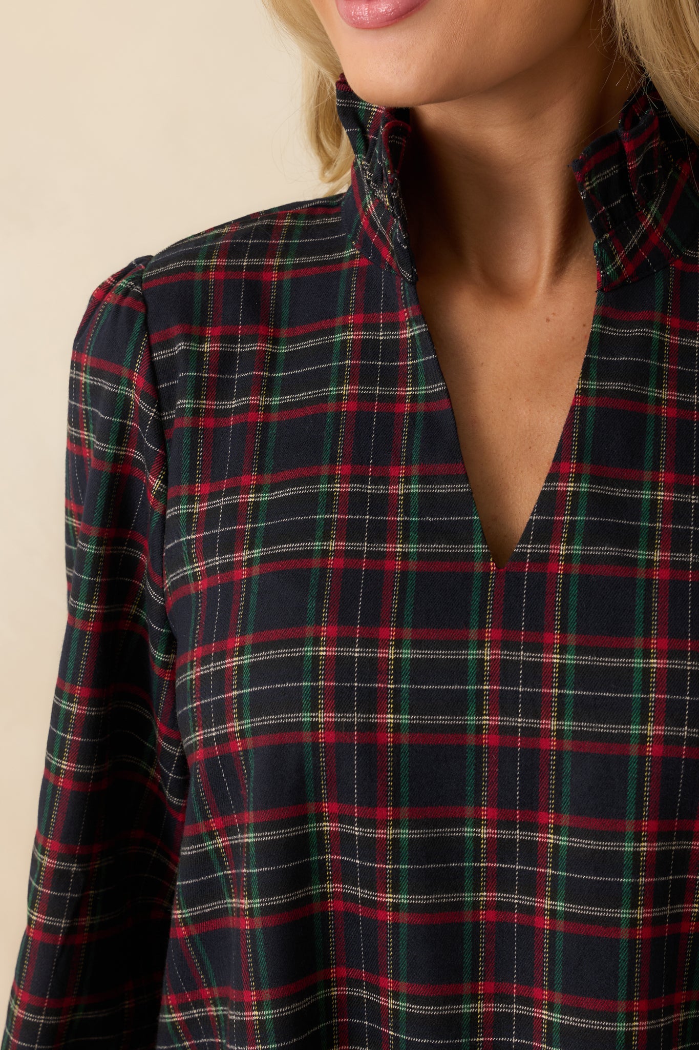 Soft woven flannel fabric with navy multi plaid pattern, showing standing collar, split neckline, and ruffle hem texture.