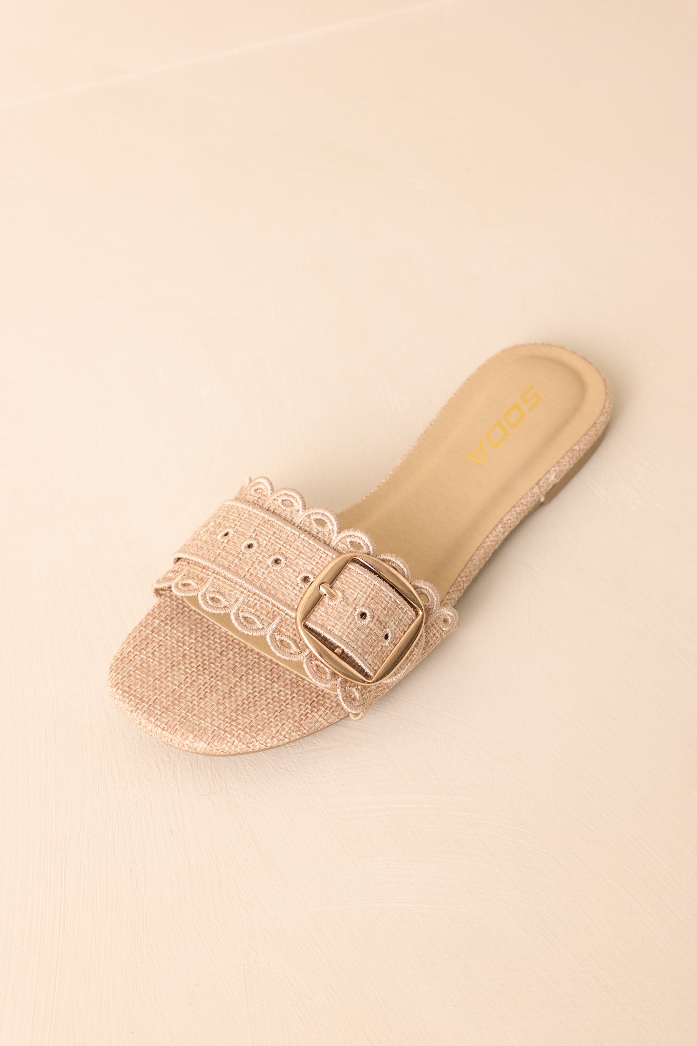 Woven sandals featuring embroidered eyelet detailing and decorative buckle accents.