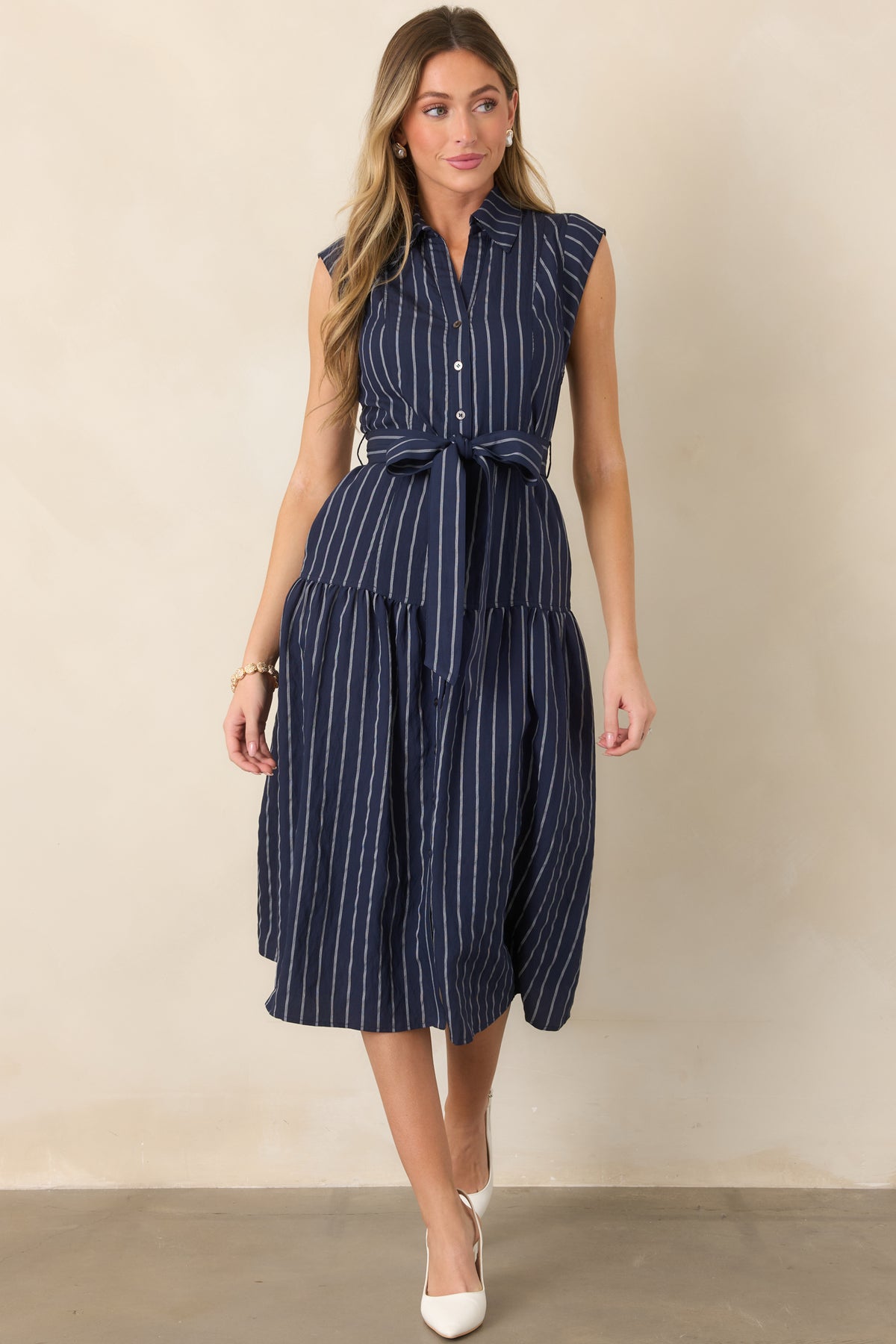 Woven sleeveless dress highlighting the functional button-front design, elongated stripe pattern, and gently gathered skirt.