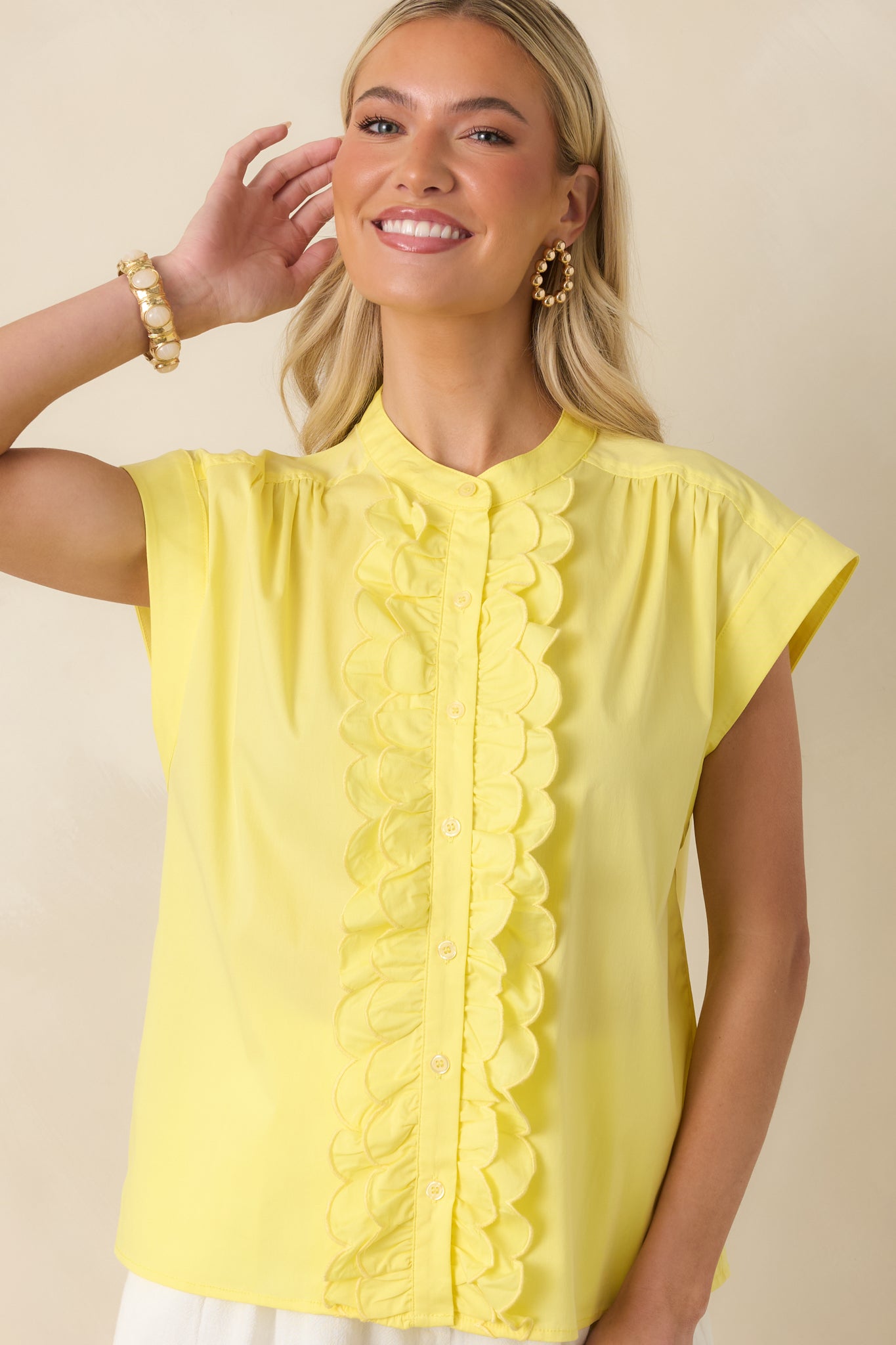 Detailed view of the yellow button-front top showcasing the scalloped ruffle trim and clean stitching along the placket.