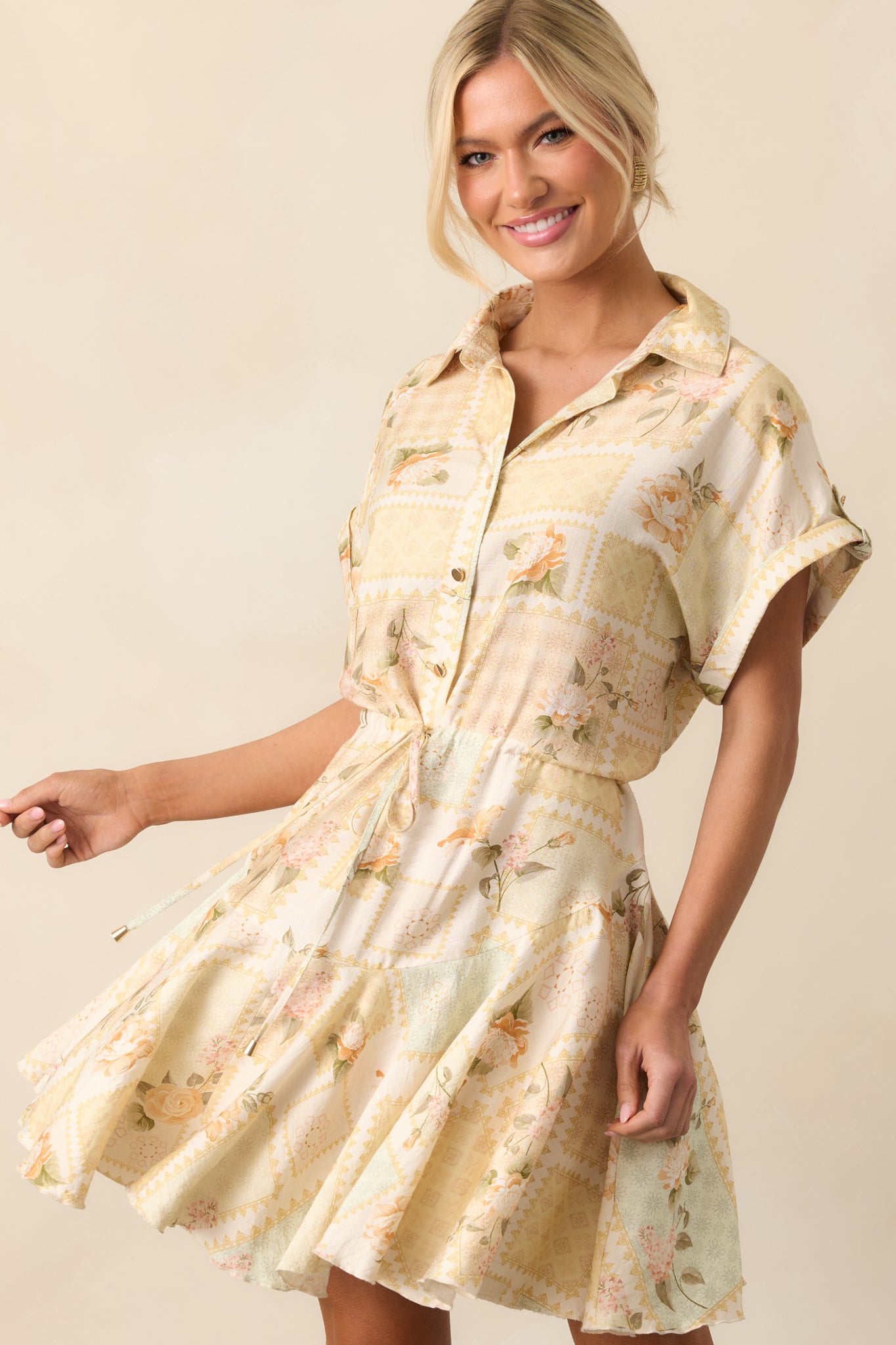 A front view of the yellow mini dress featuring a collared neckline, gold front buttons, and flared skirt shown in movement.