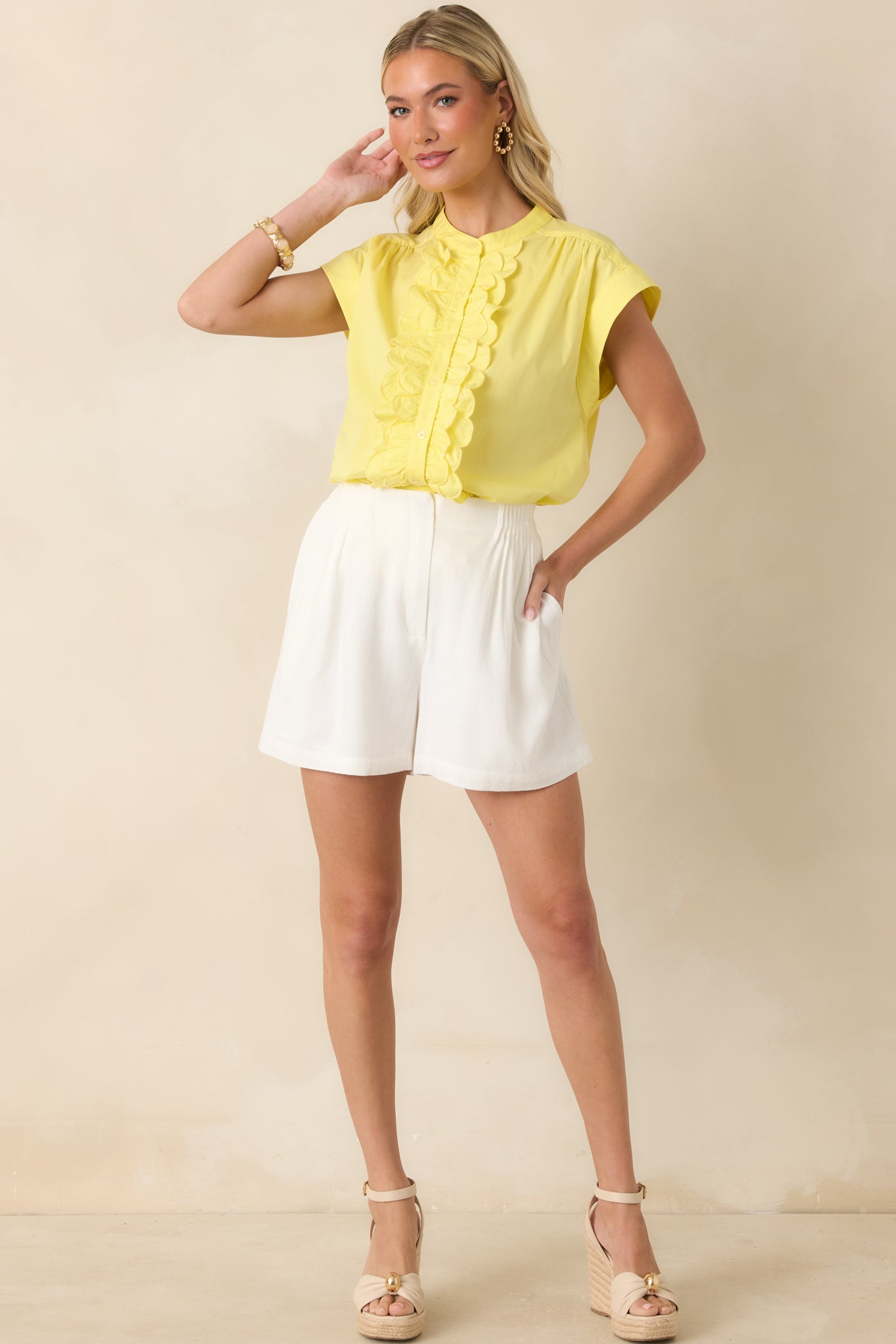 Yellow cotton blend top featuring a band collar, scalloped ruffle front detailing, and a functional button-front closure with soft gathered shoulder accents.