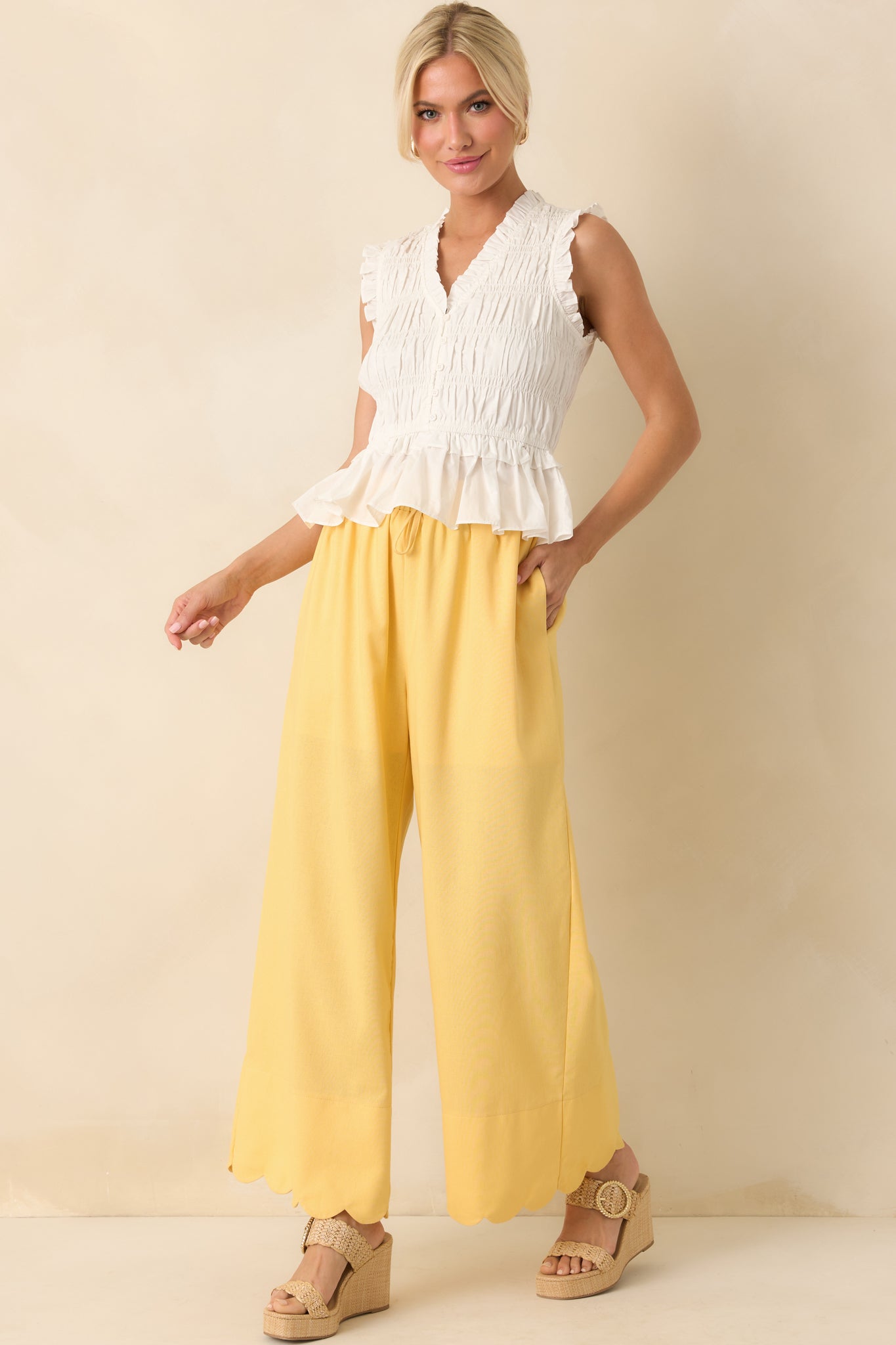 Yellow high-waisted pants with a self-tie elastic waistband and wide leg silhouette shown from the front, featuring functional side pockets.
