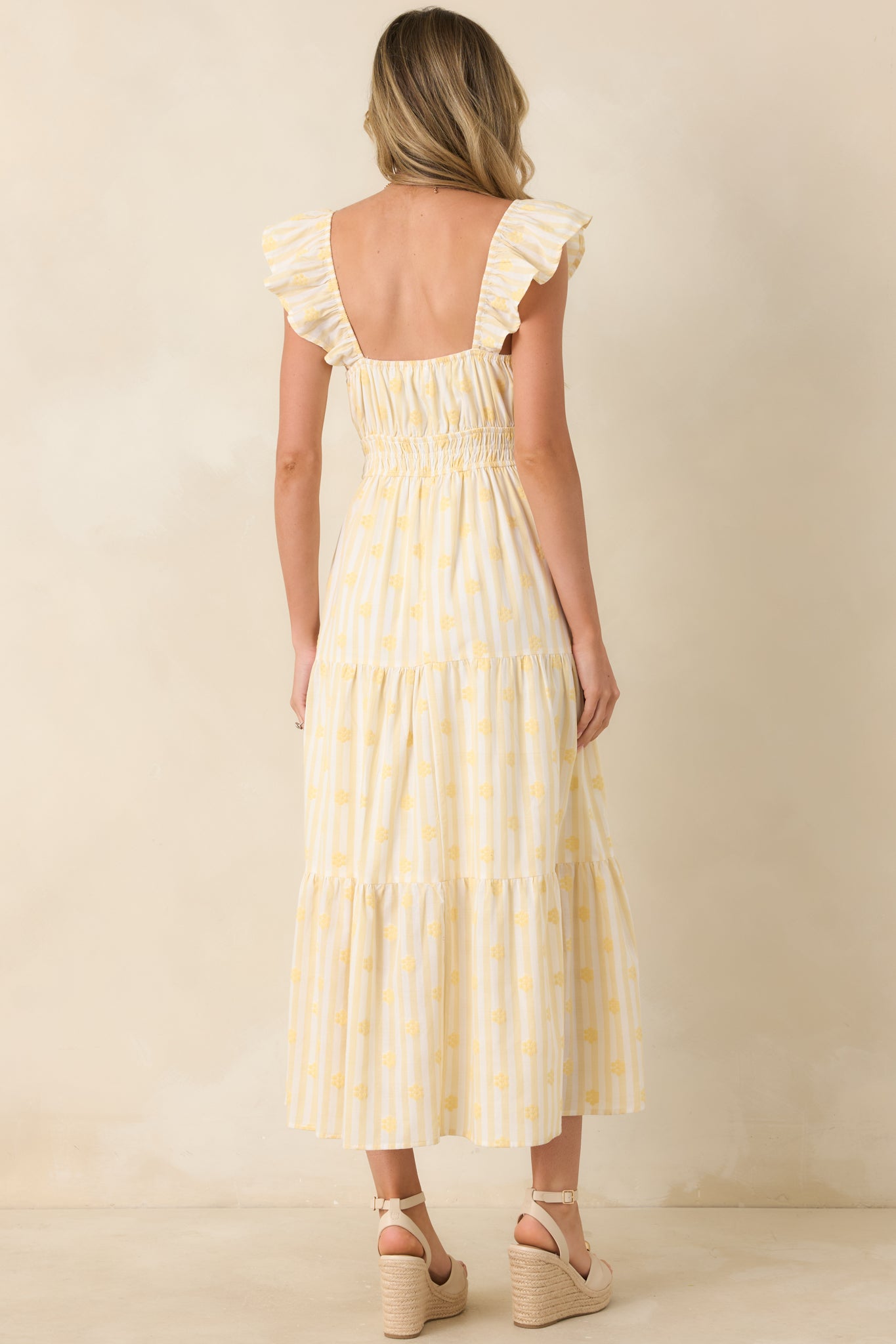 Back view of the yellow stripe floral maxi dress highlighting the gathered neckline, flutter sleeves, and flowing tiered design.