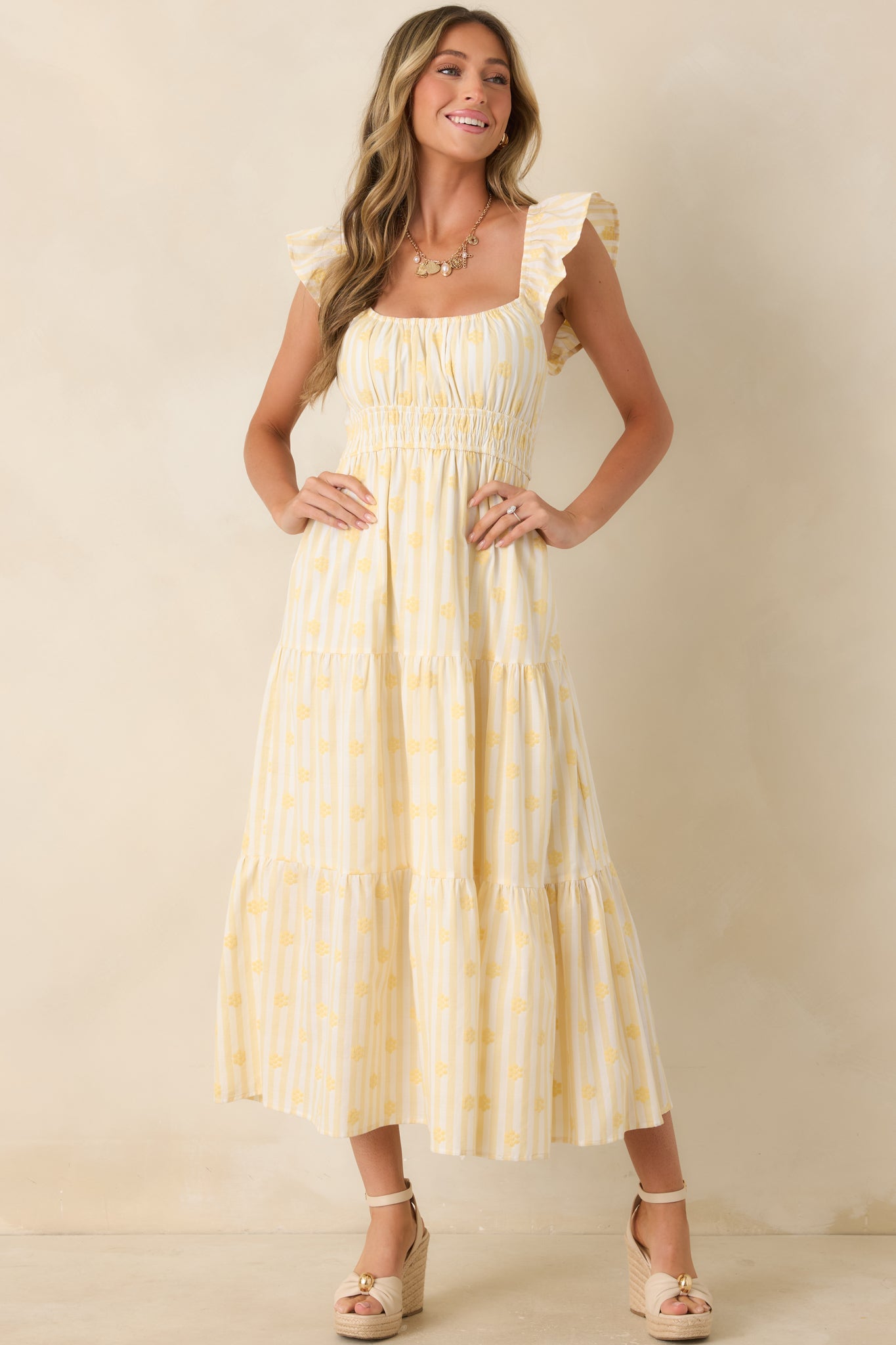 Yellow floral maxi dress showcasing an elasticized smocked waistband and embroidered accents throughout the cotton fabric.