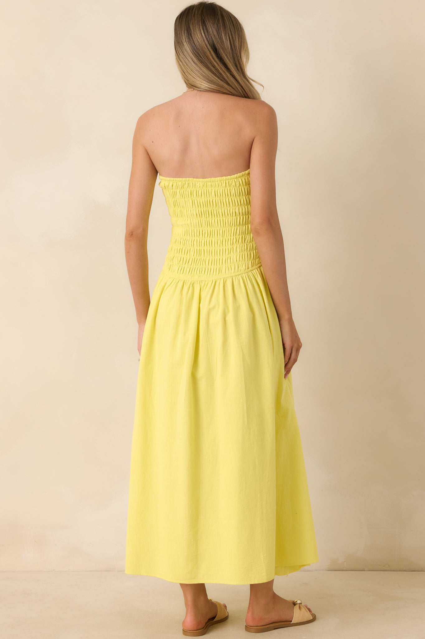 Back view of the yellow maxi dress featuring a strapless smocked bodice, flowy gathered skirt, and pull-on construction.