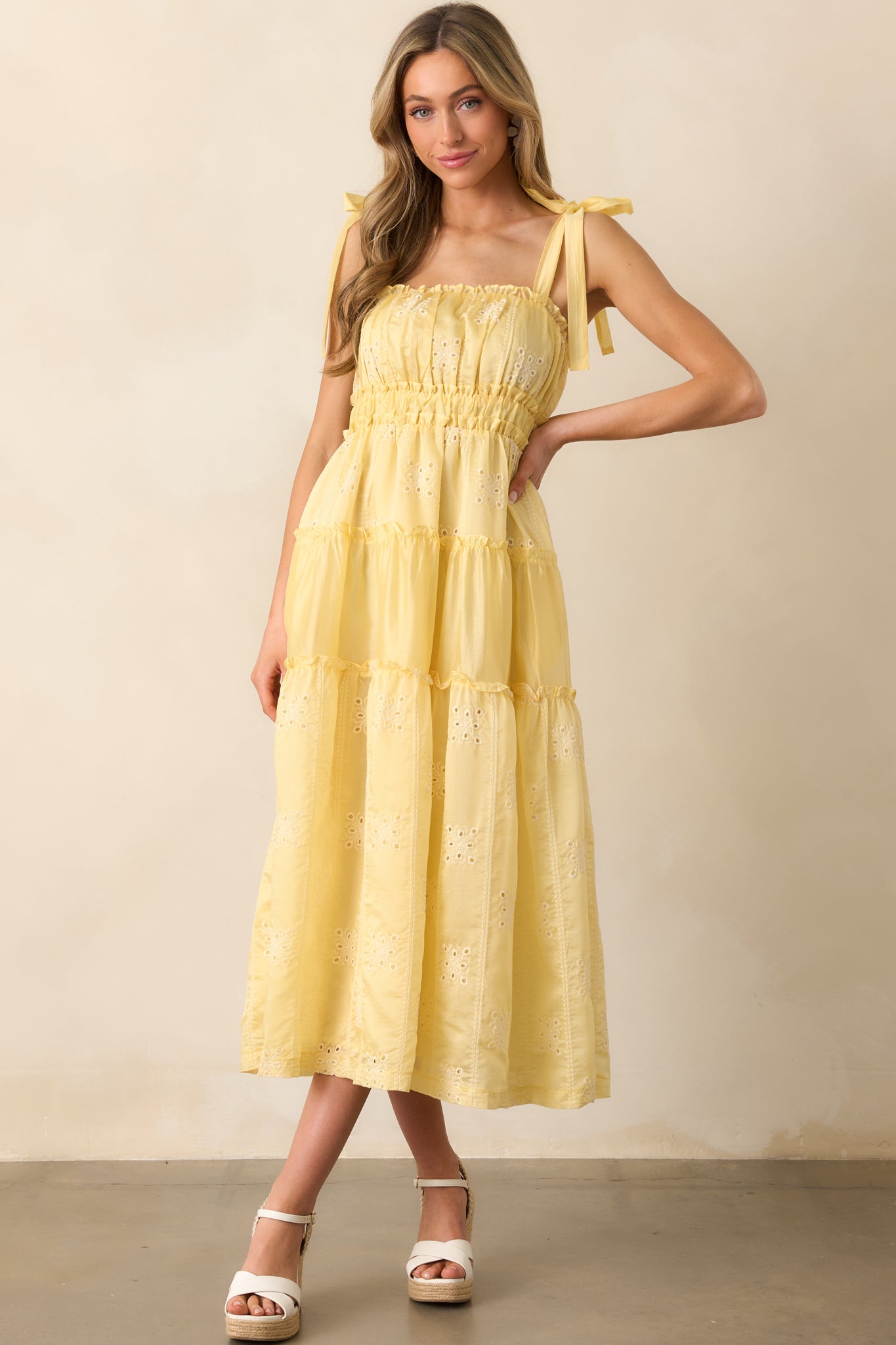 A yellow midi dress with a square neckline, ruffle trim details, and delicate embroidered eyelet accents.