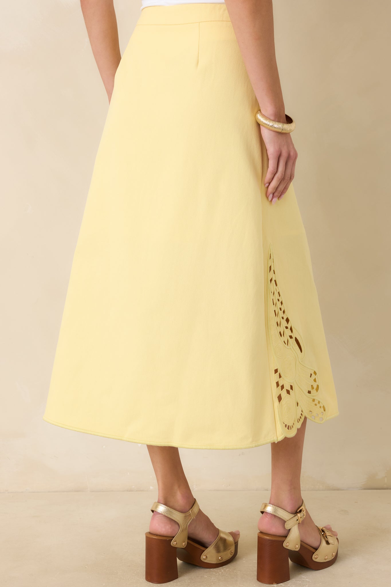 Back view of the yellow midi skirt featuring a concealed side zipper closure, structured waistband, and A-line silhouette.