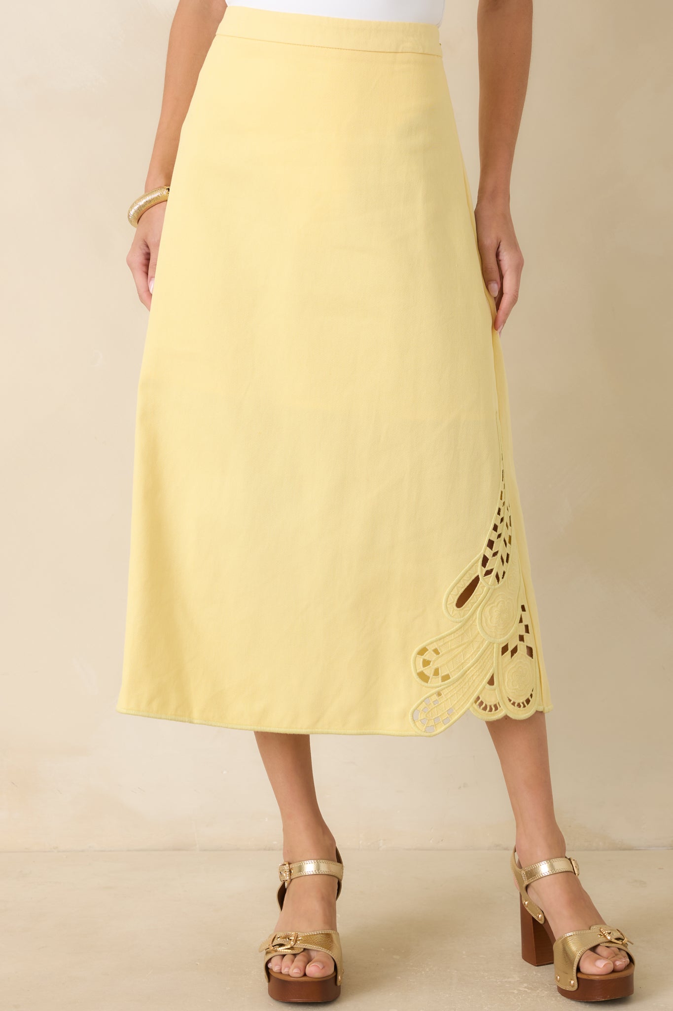 Close view of the high-rise waistband and structured cotton construction of the yellow midi skirt.