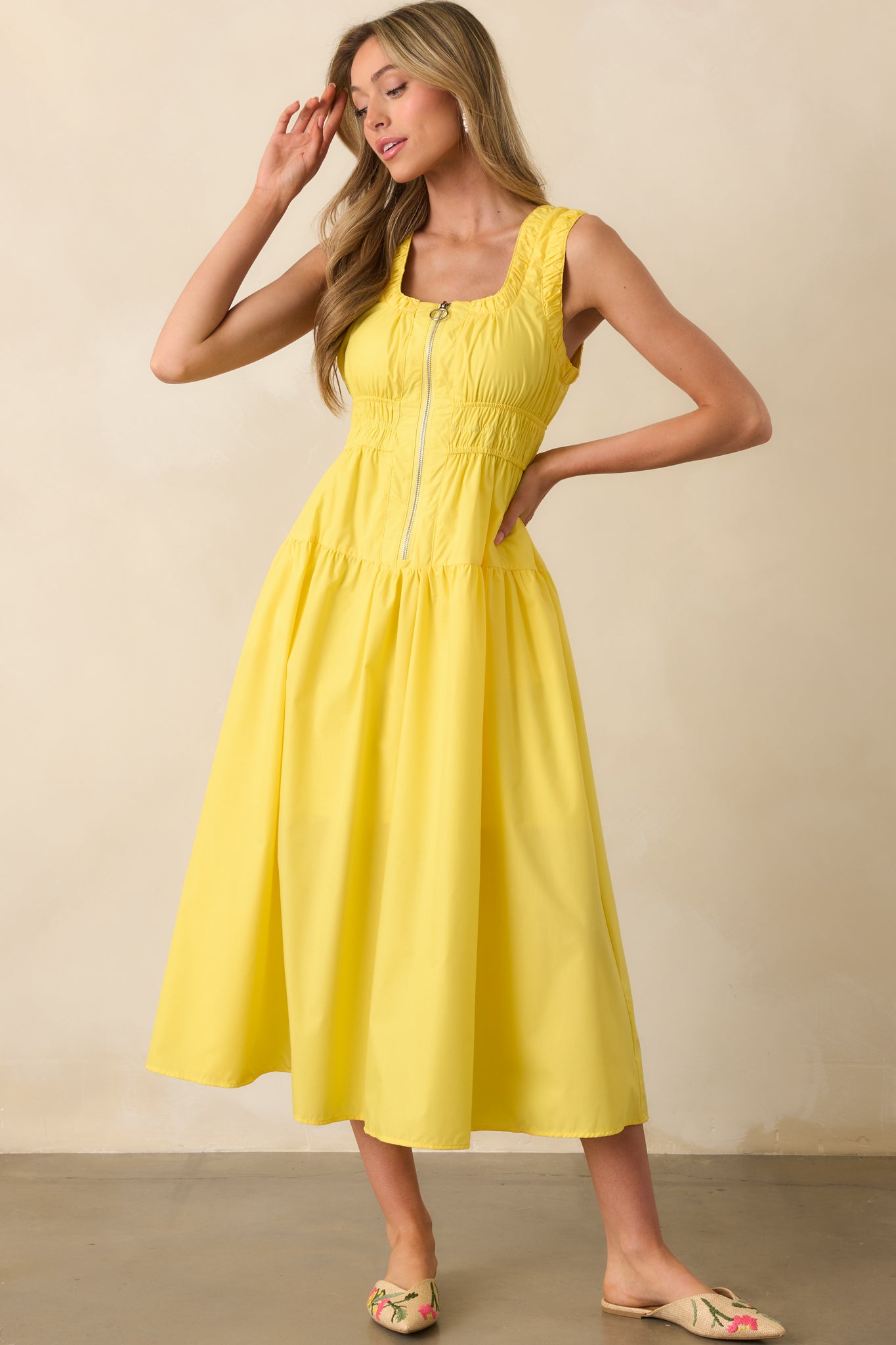 Full-length front-facing view of a yellow sleeveless dress, with elastic ruched waist and detailed hem ruching.